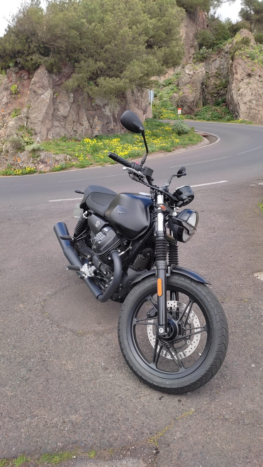 A black motorcycle is parked on the side of a road.