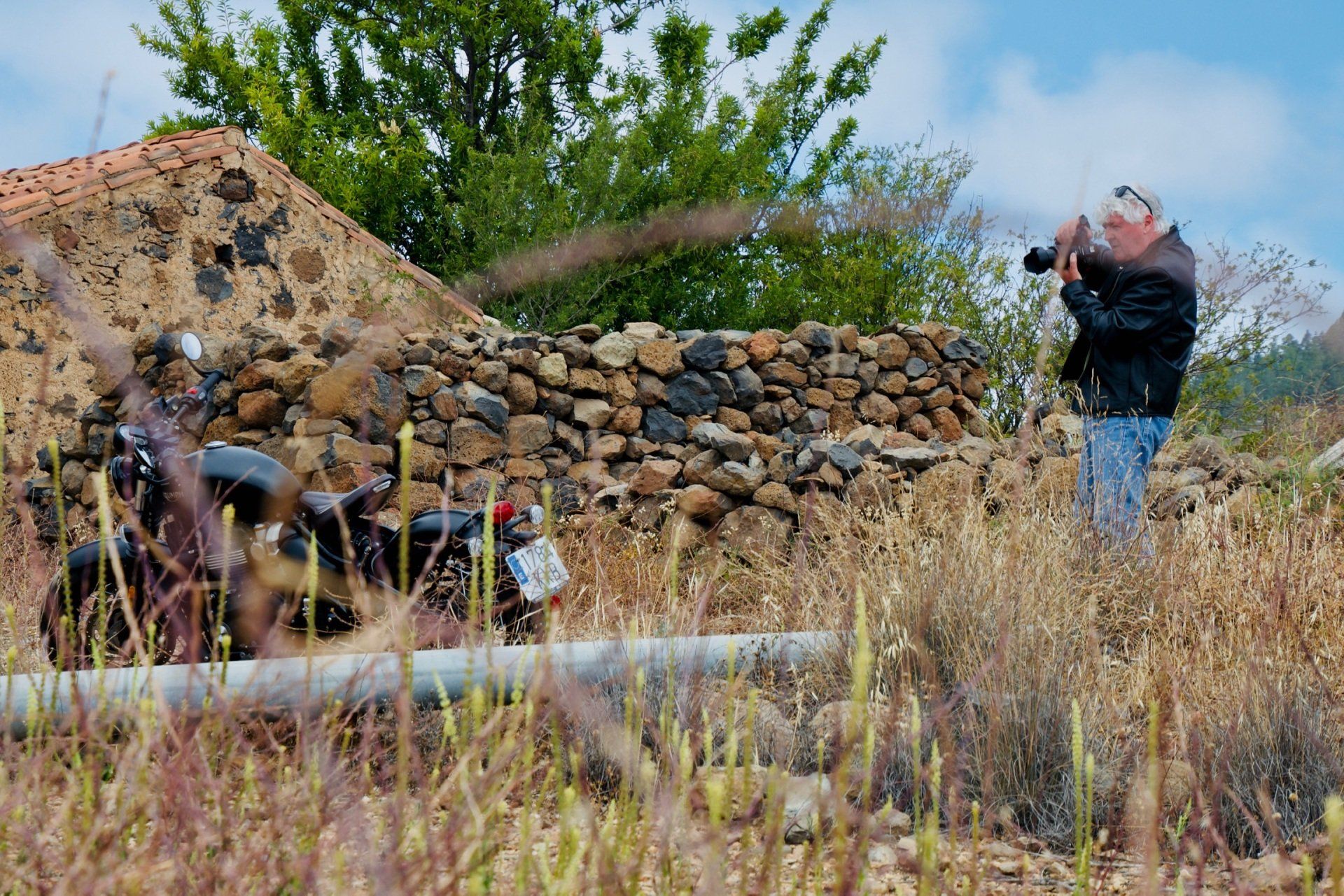 A man is taking a picture of a motorcycle in a field.