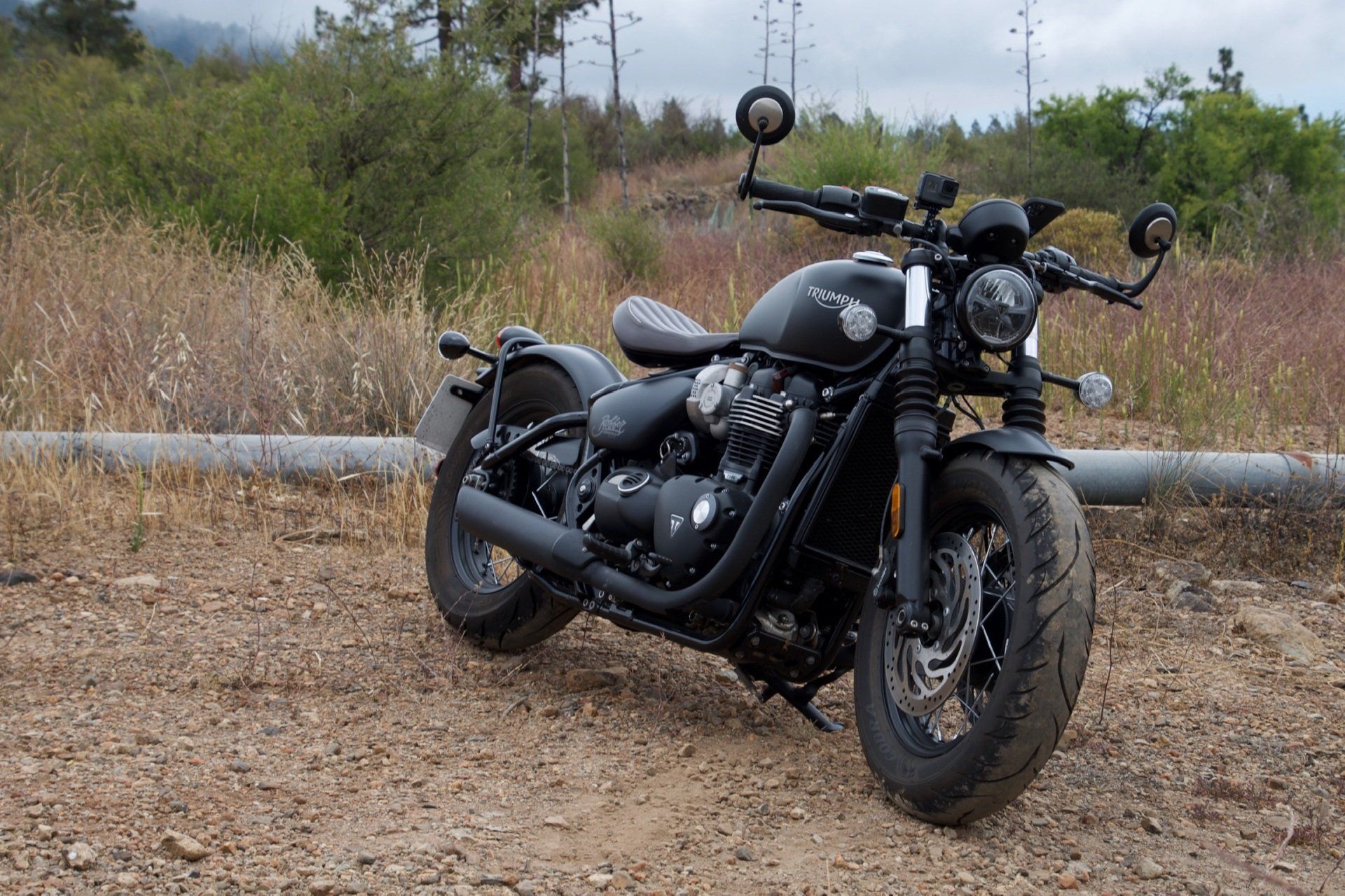 A black motorcycle is parked on a dirt road.