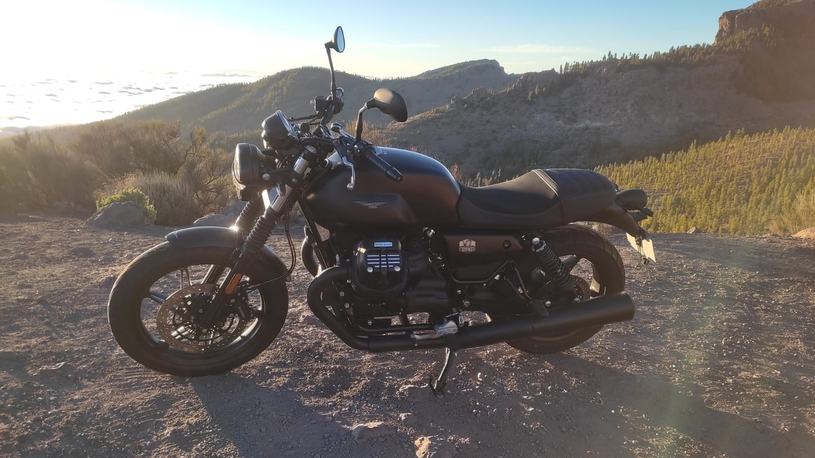 A black motorcycle is parked on the side of a dirt road