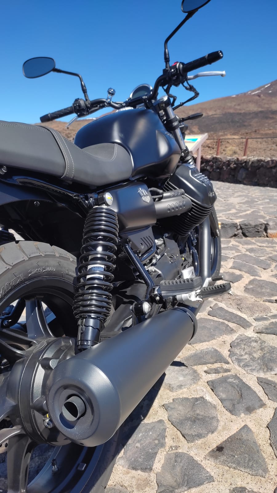 A black motorcycle is parked on a cobblestone road.