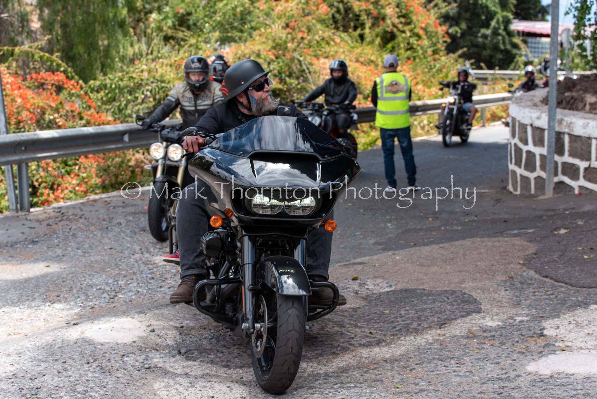 A group of men are riding motorcycles down a road.