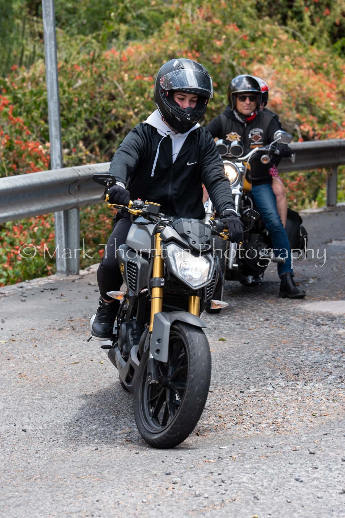 Two people are riding motorcycles down a road.