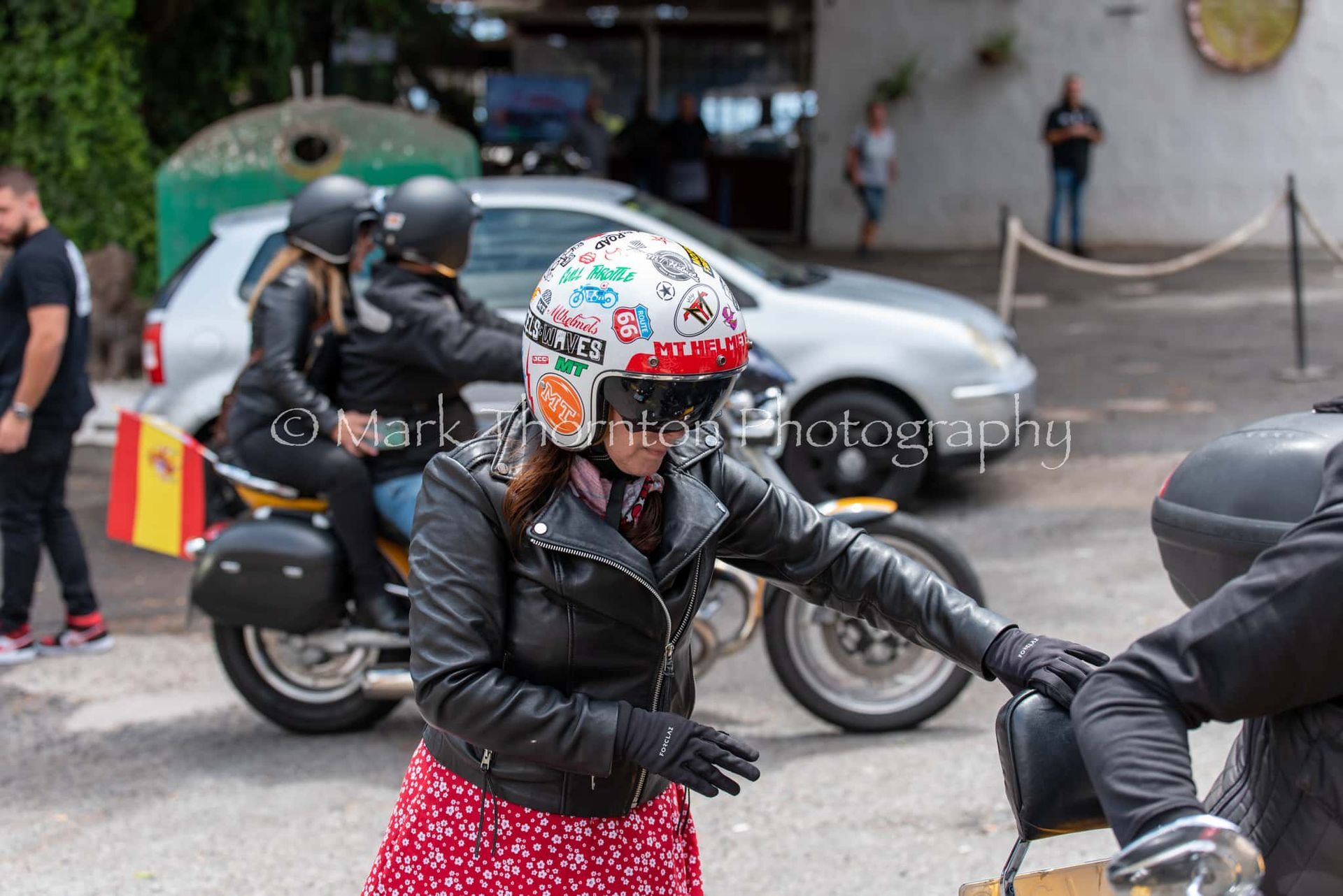 A woman wearing a helmet is shaking hands with a man on a motorcycle.