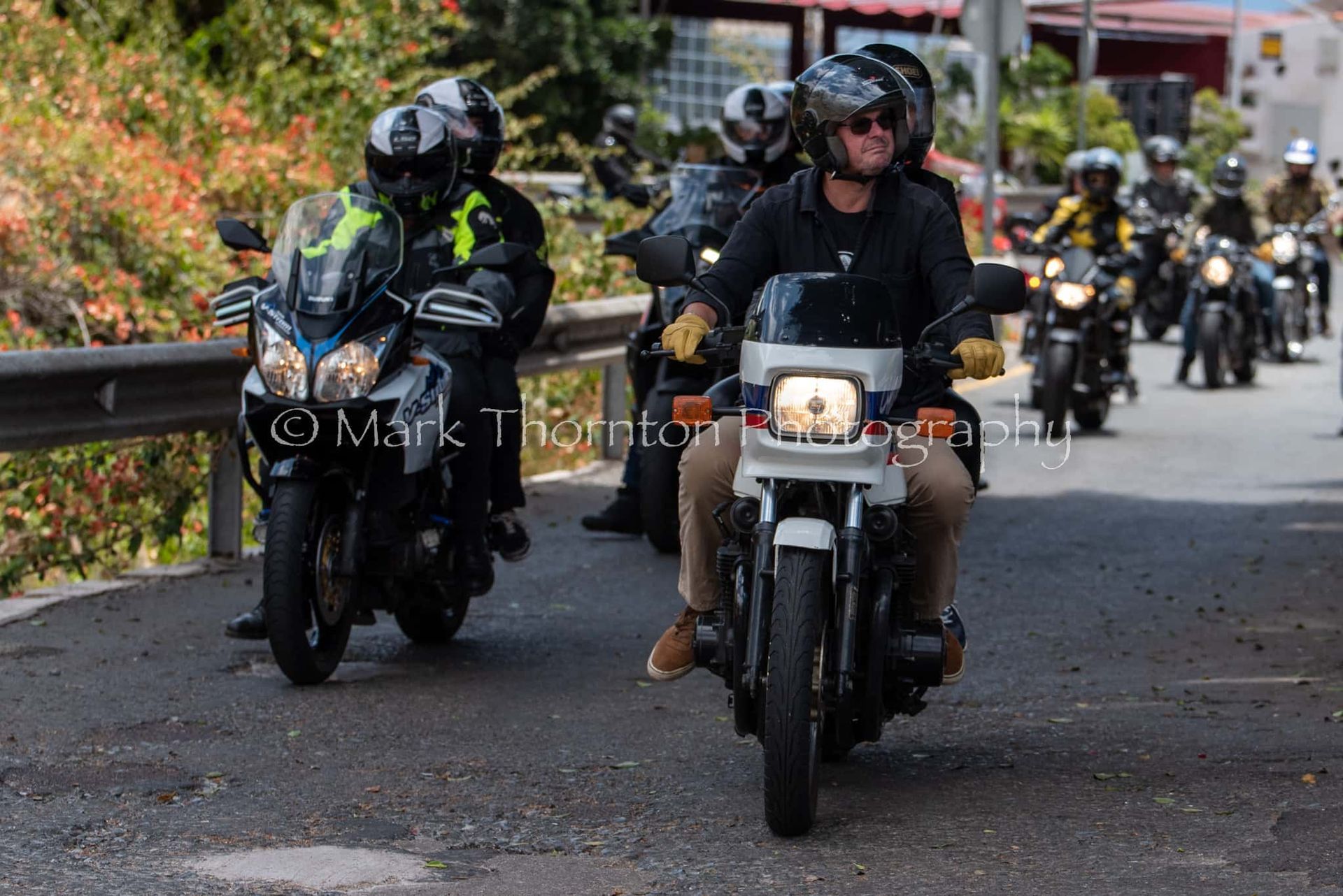 A group of people are riding motorcycles down a road.