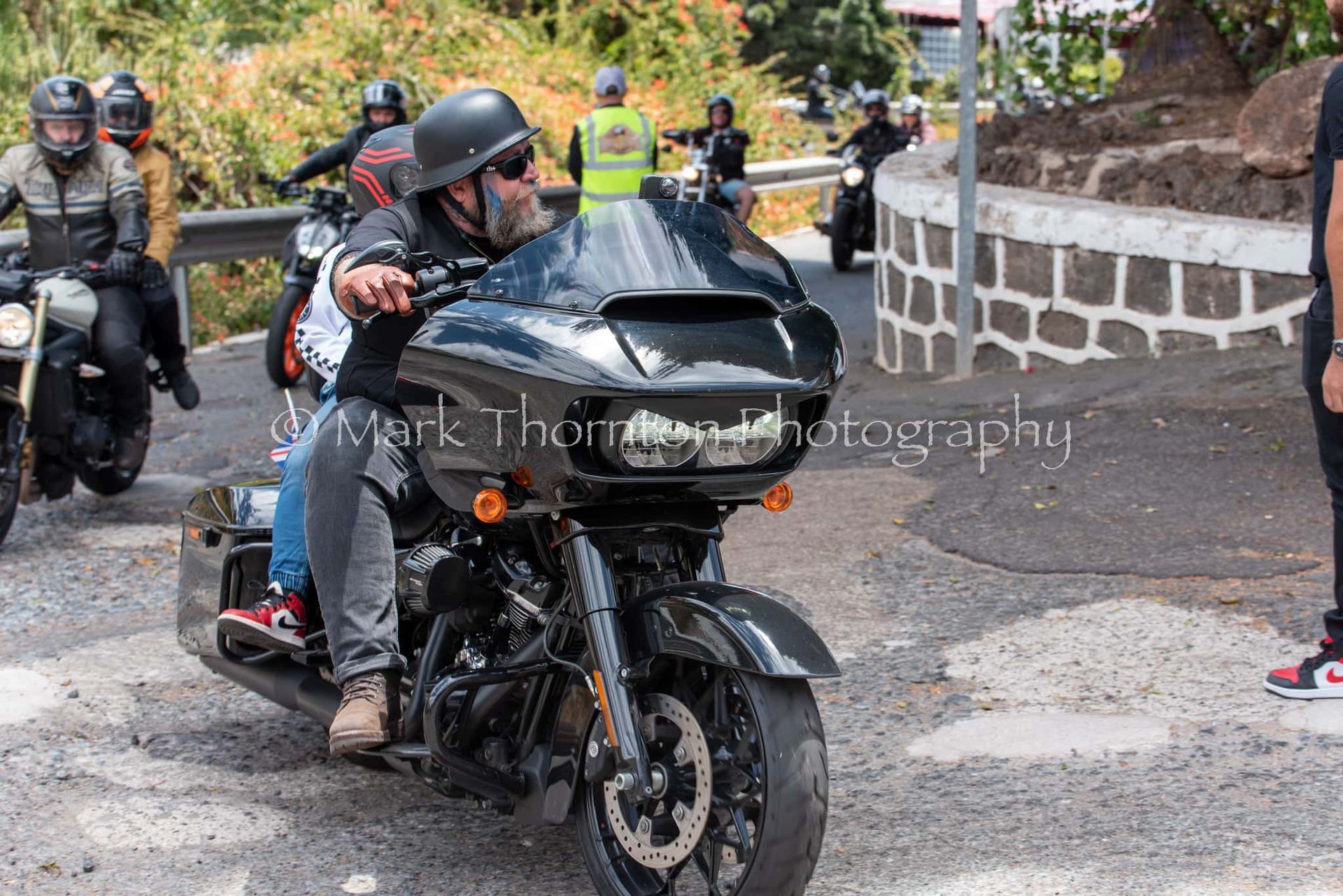 A group of people are riding motorcycles down a road.