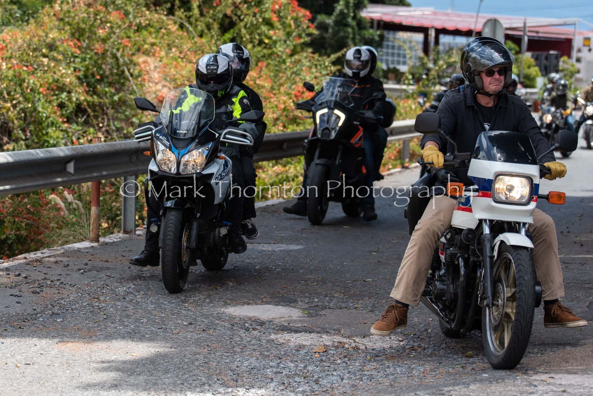 A group of people are riding motorcycles down a road