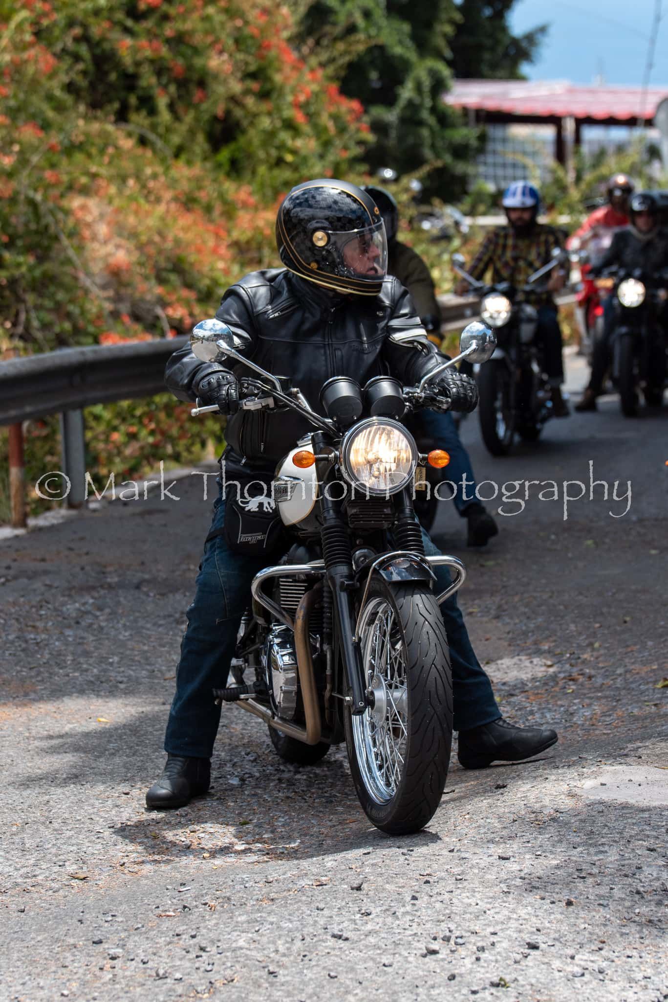 A man is riding a motorcycle down a dirt road.