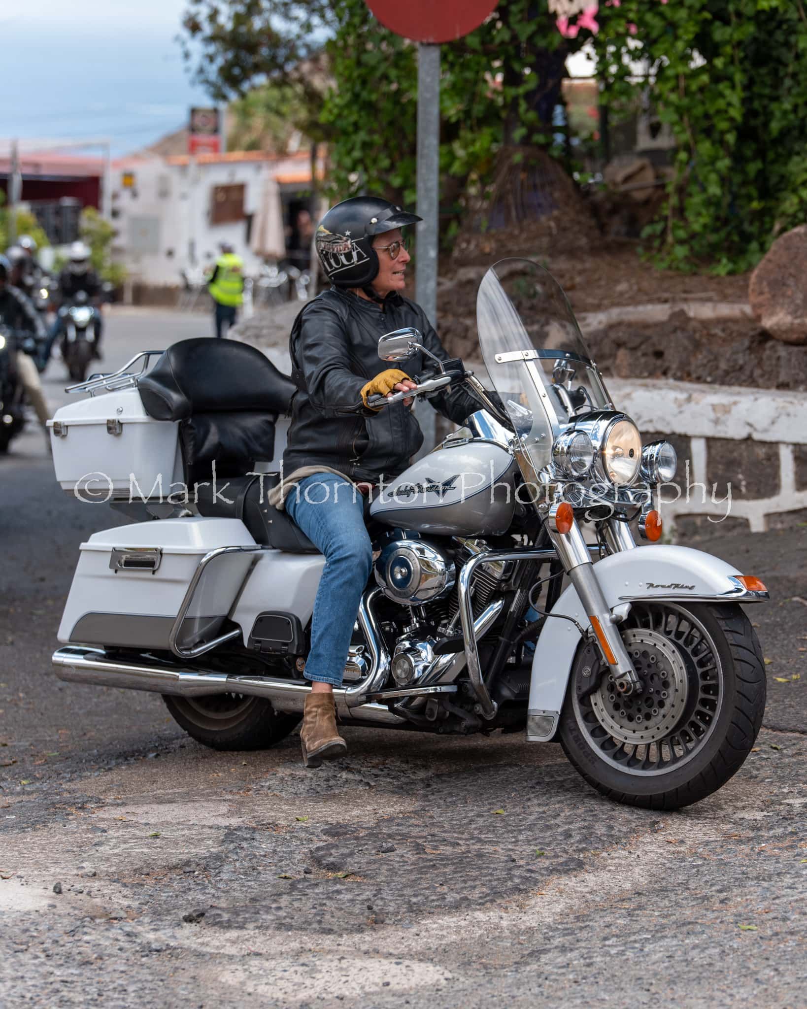 A man is riding a harley davidson motorcycle down a street.