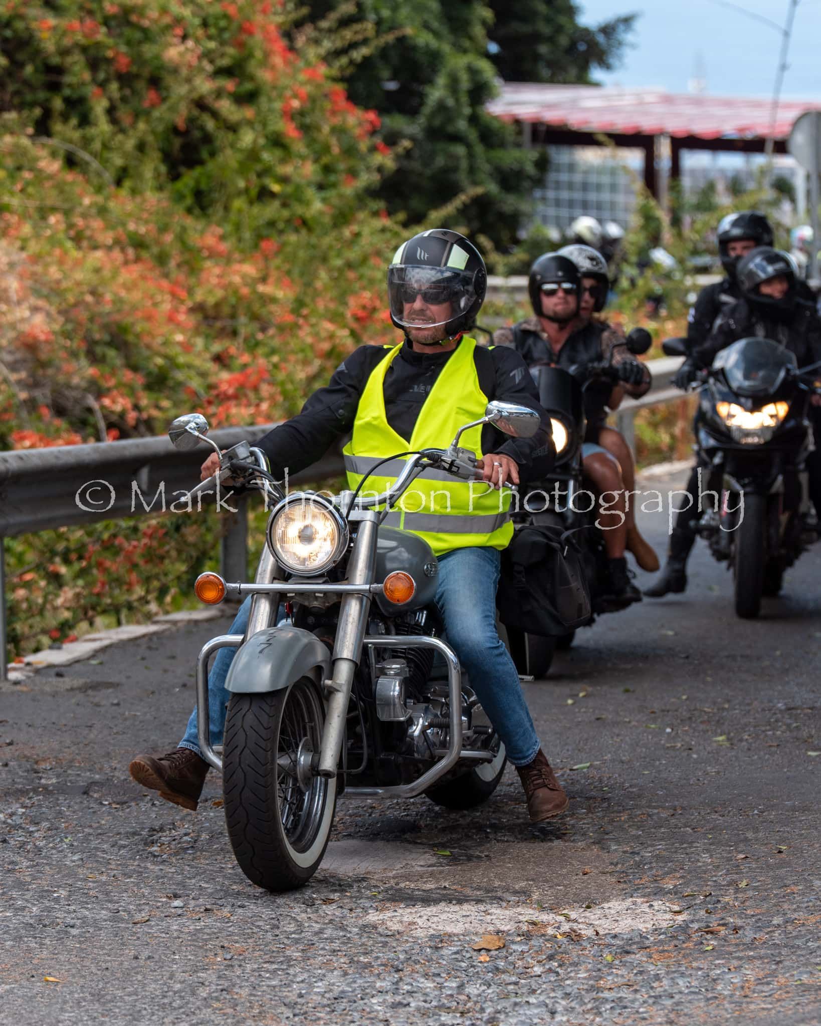 A group of people are riding motorcycles down a road.