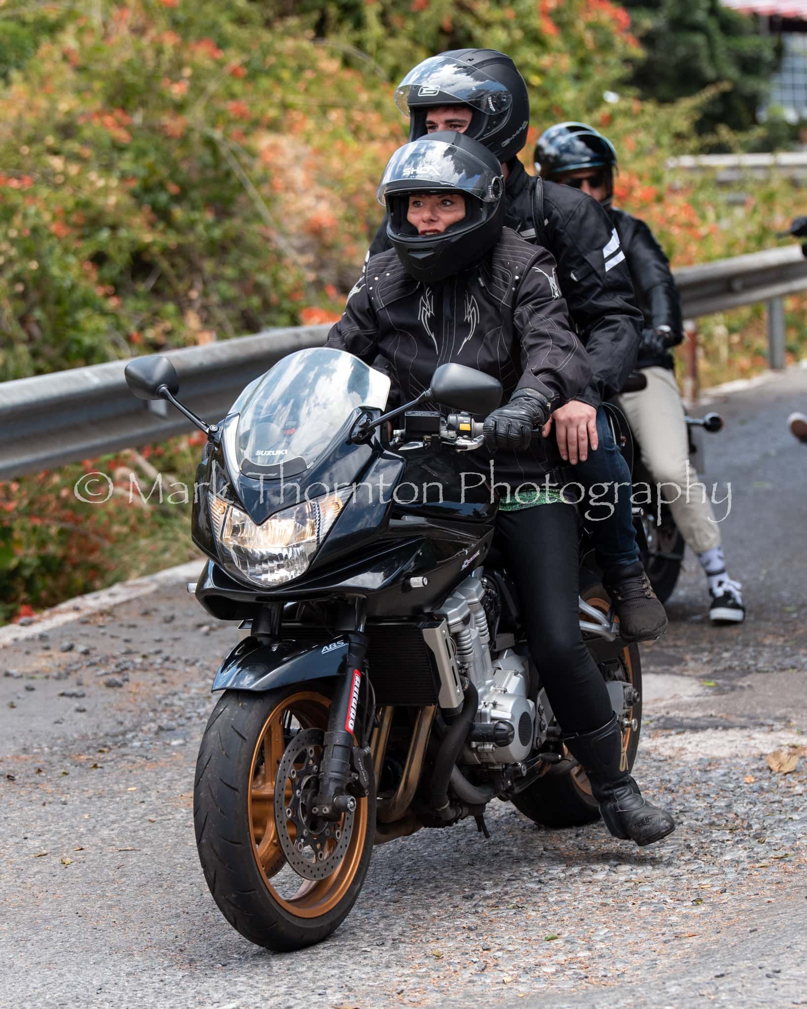 A man and a woman are riding a motorcycle down a road.