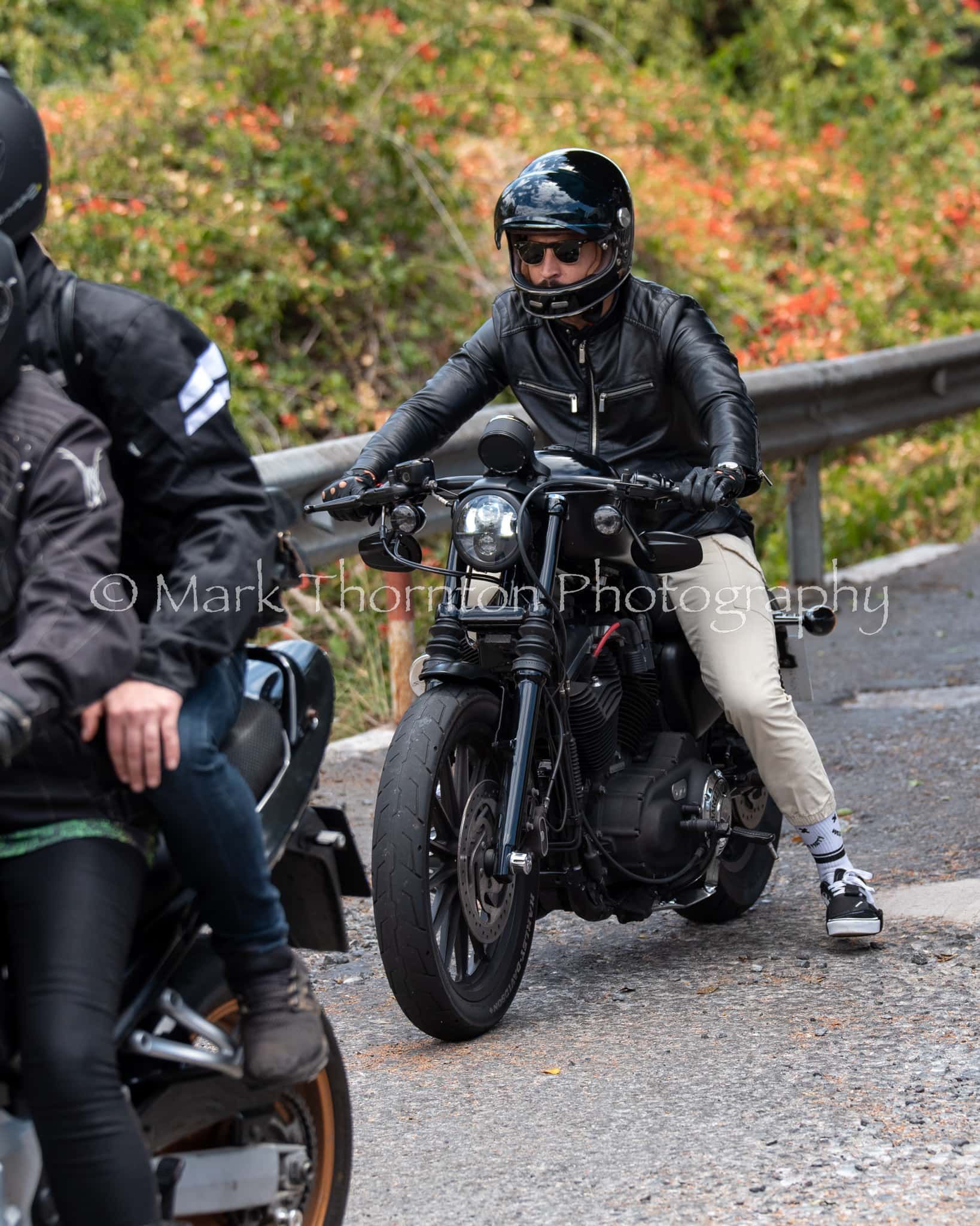 A man wearing a helmet is riding a motorcycle down a road.