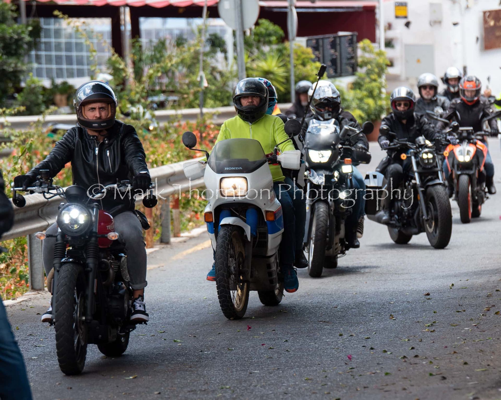 A group of people are riding motorcycles down a street