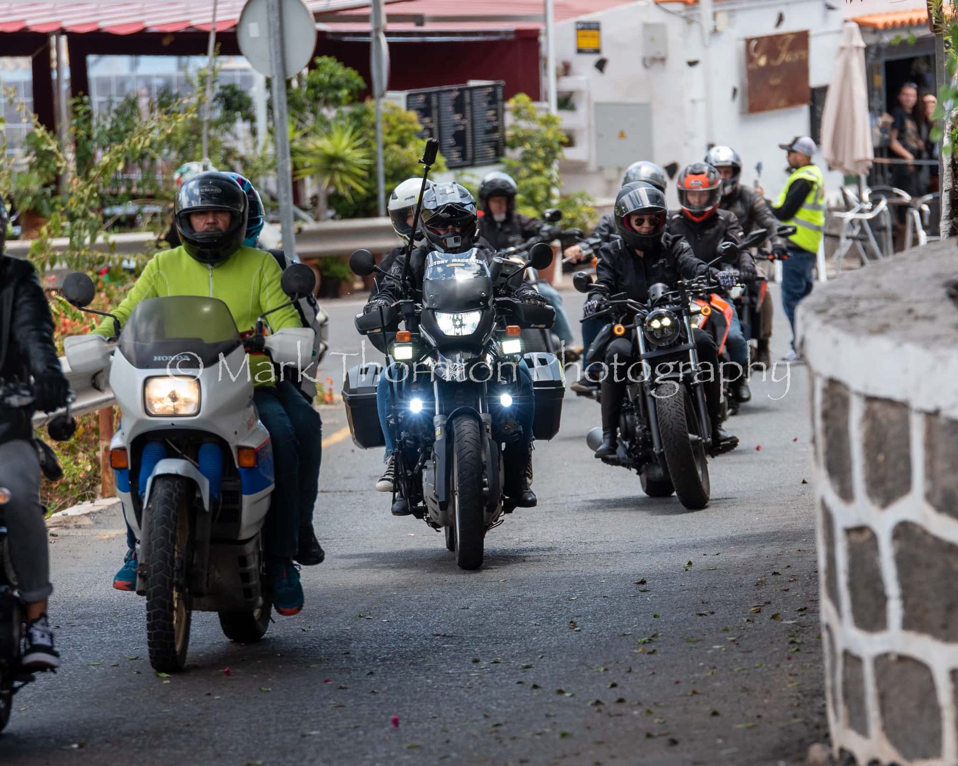A group of people are riding motorcycles down a street