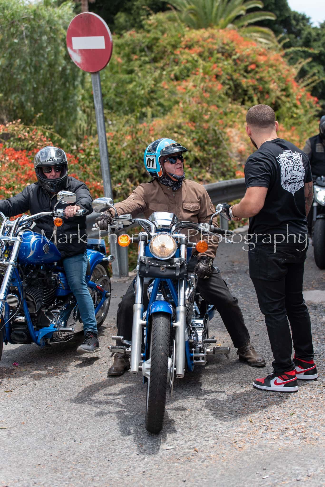 A group of men are riding motorcycles down a street.