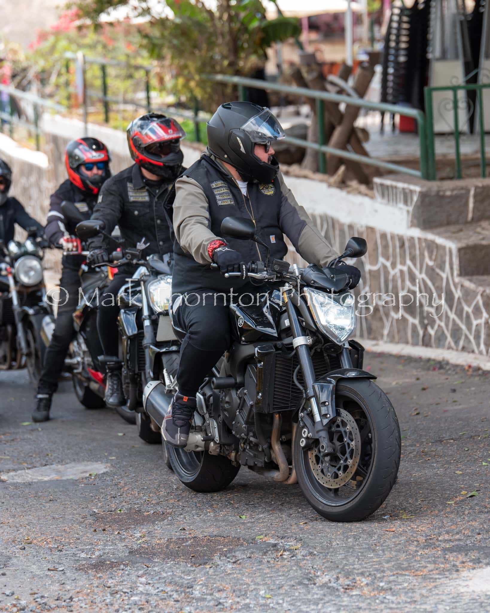 A group of men are riding motorcycles down a street.