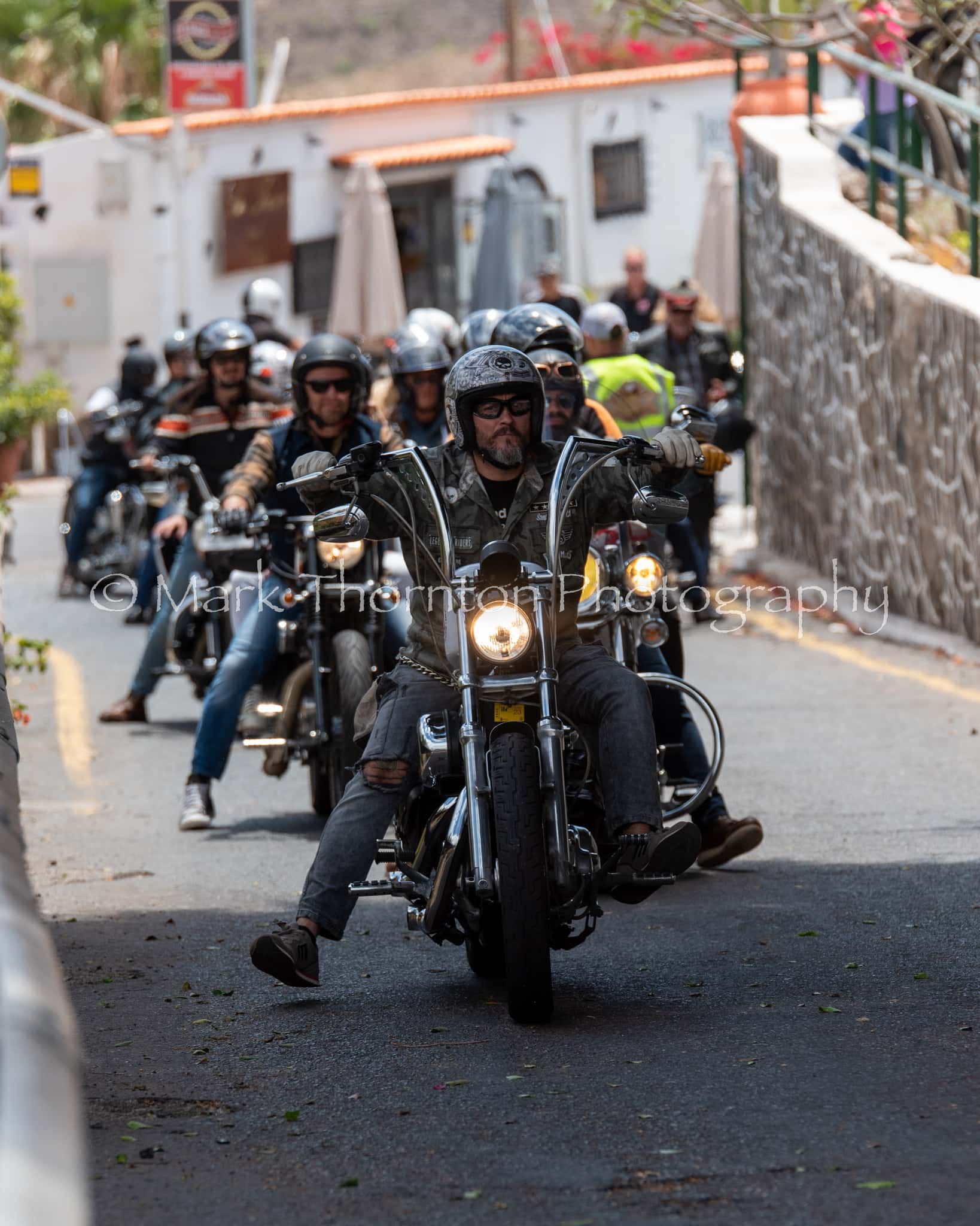 A group of men are riding motorcycles down a street