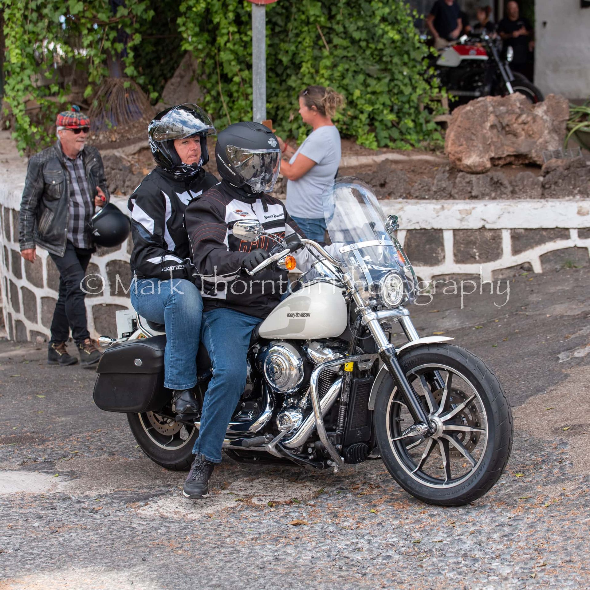 A man and woman are riding a harley davidson motorcycle