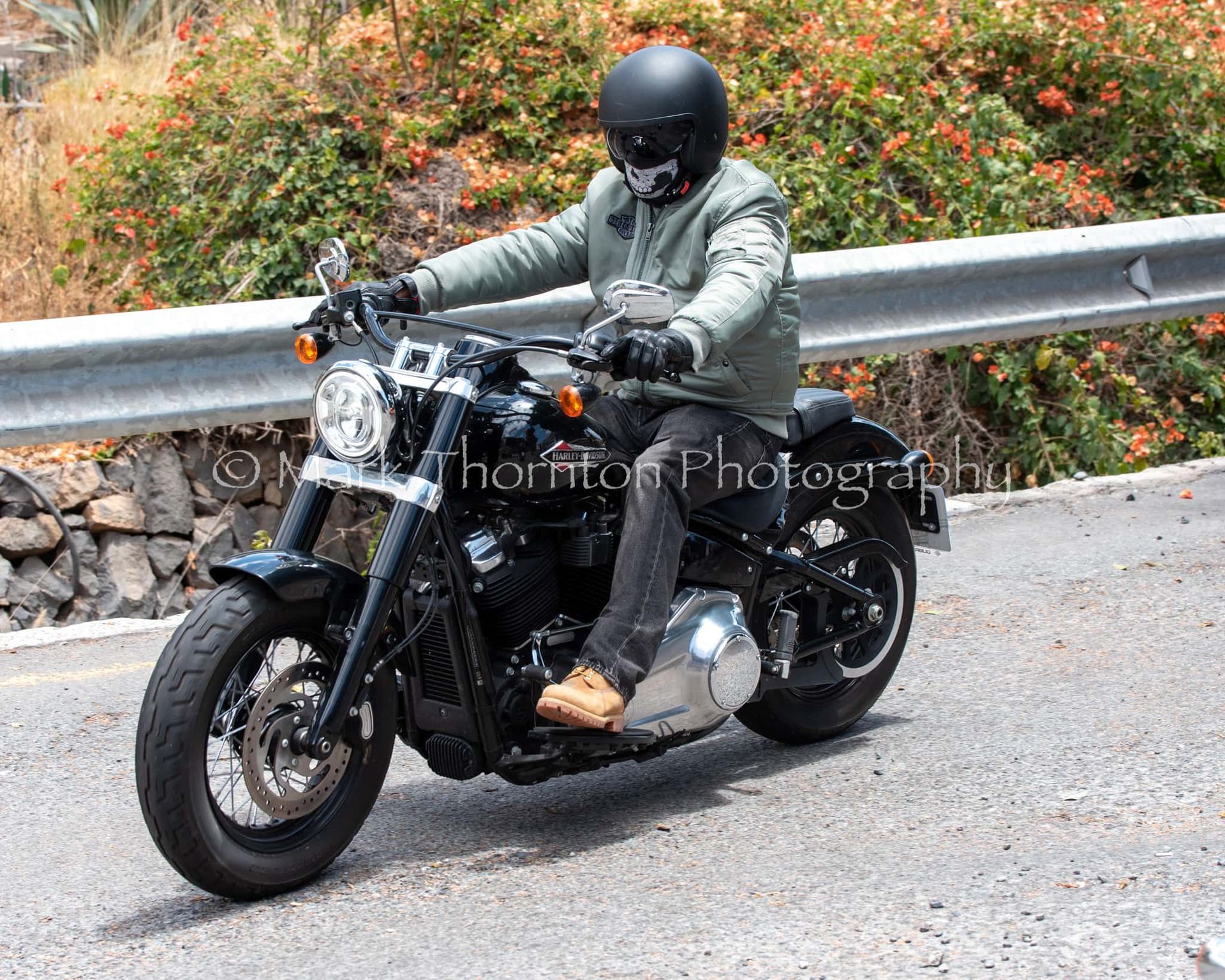 A man wearing a helmet is riding a motorcycle down a road