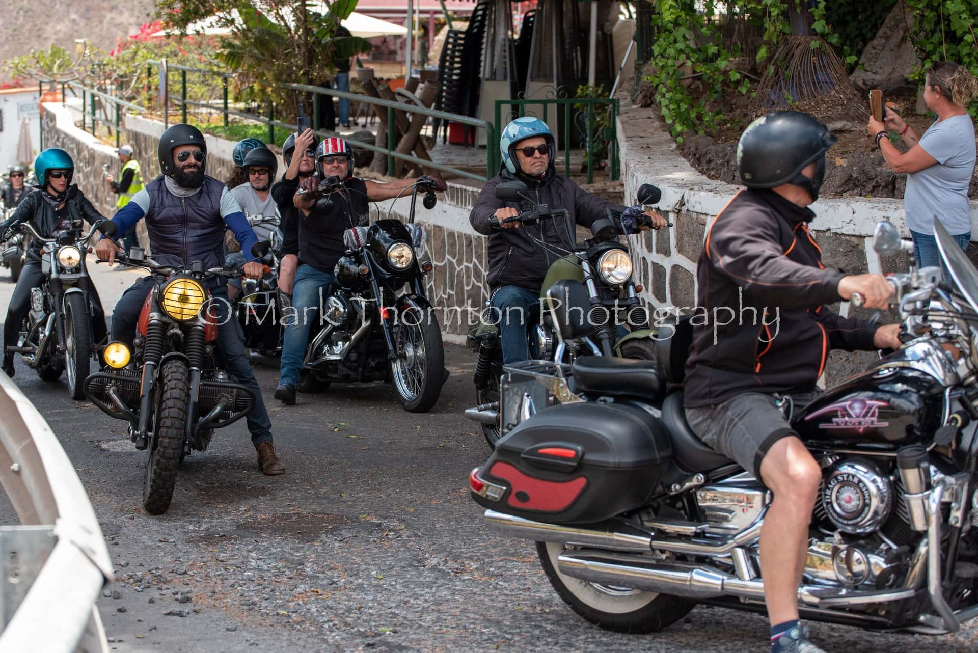 A group of men are riding motorcycles down a street.