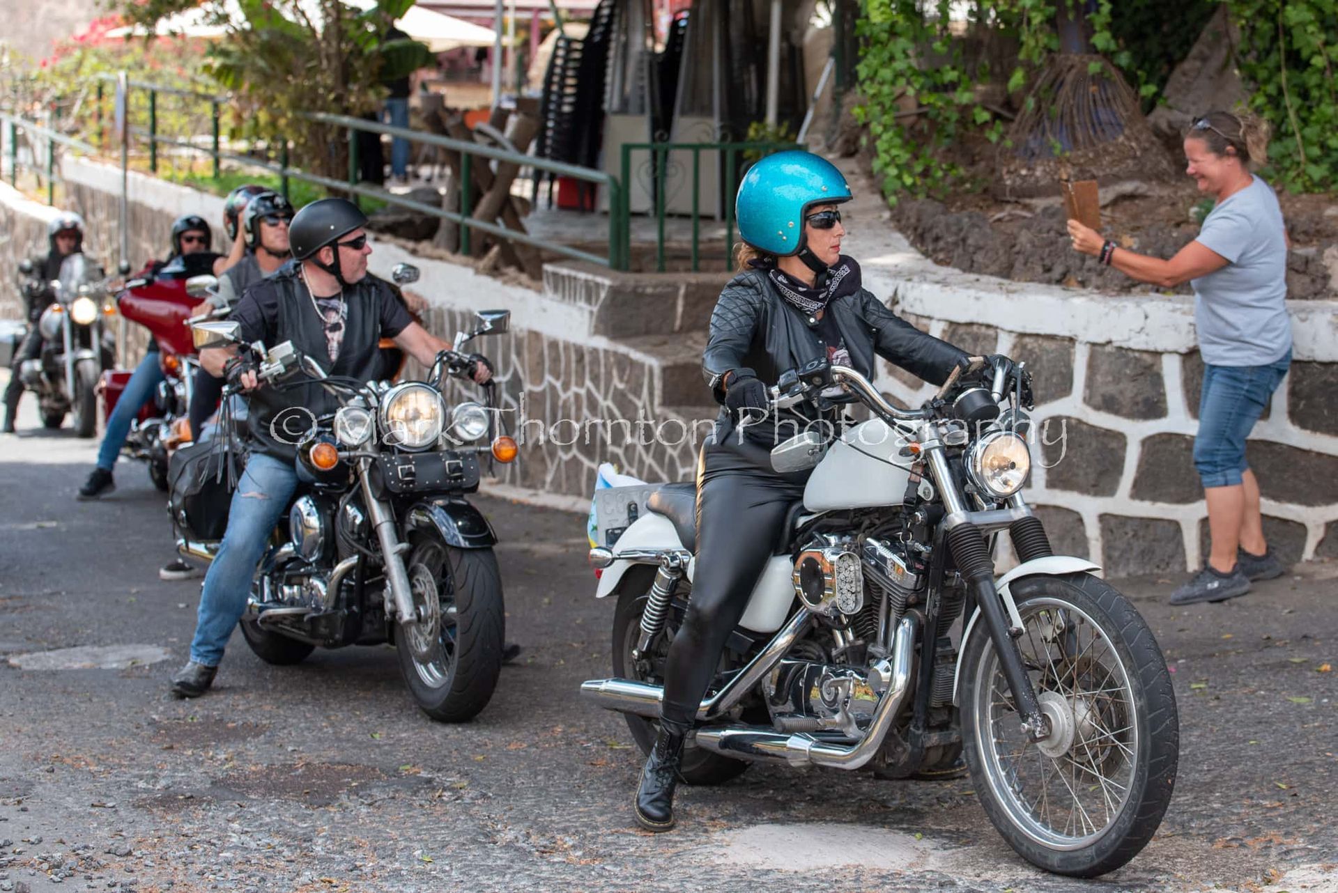 A group of people are riding motorcycles down a street