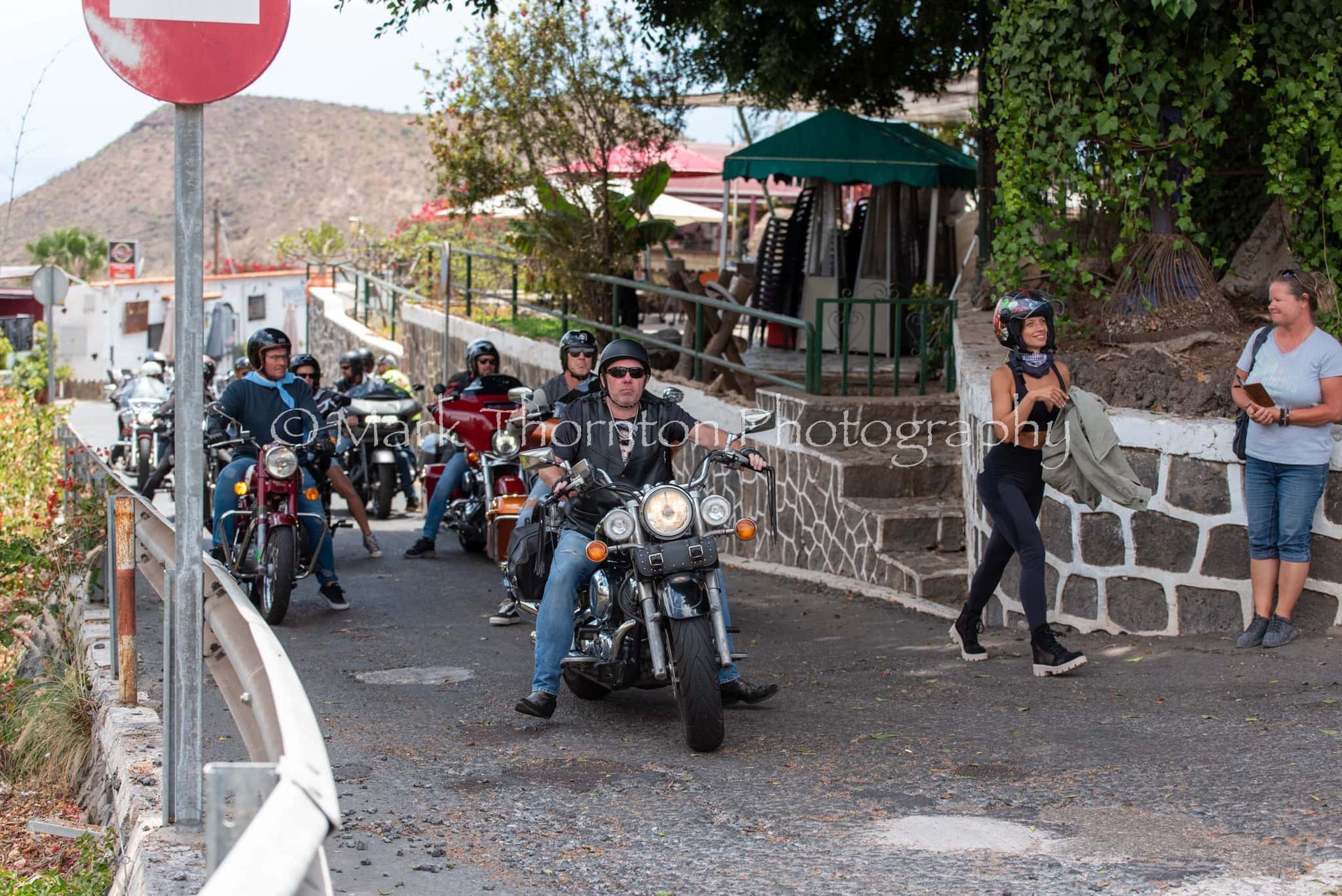A group of people are riding motorcycles down a street