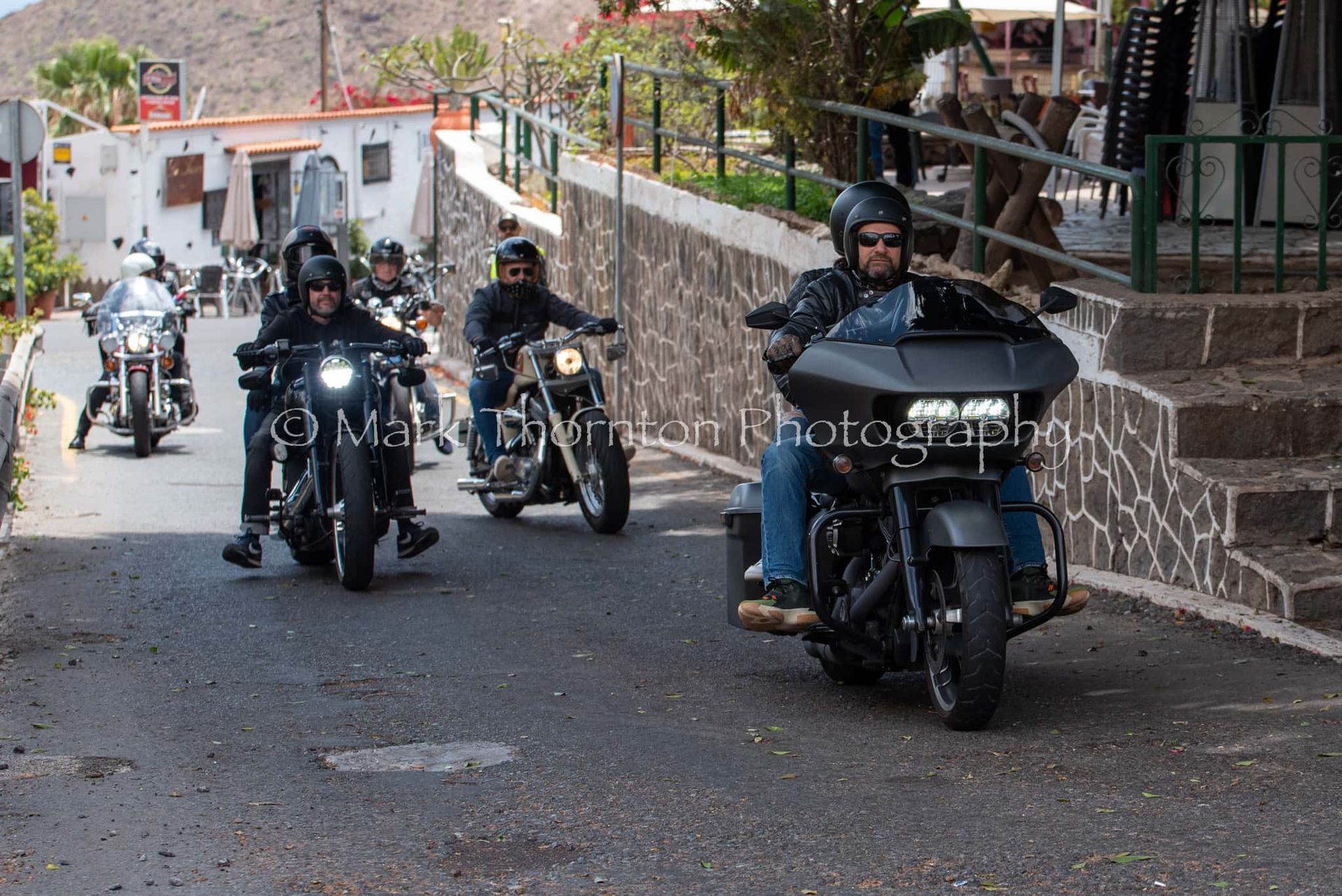 A group of men are riding motorcycles down a street