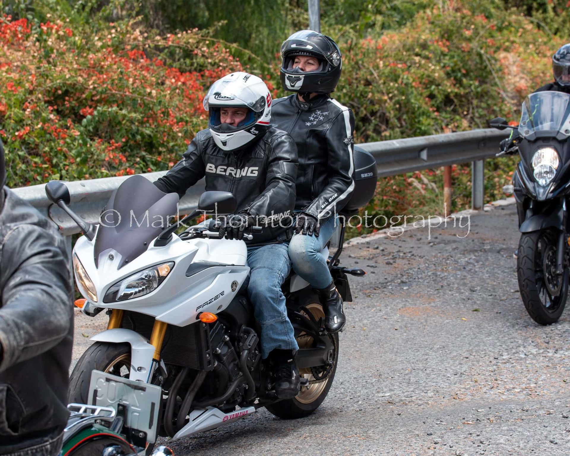 A man wearing a jacket that says racing is riding a motorcycle
