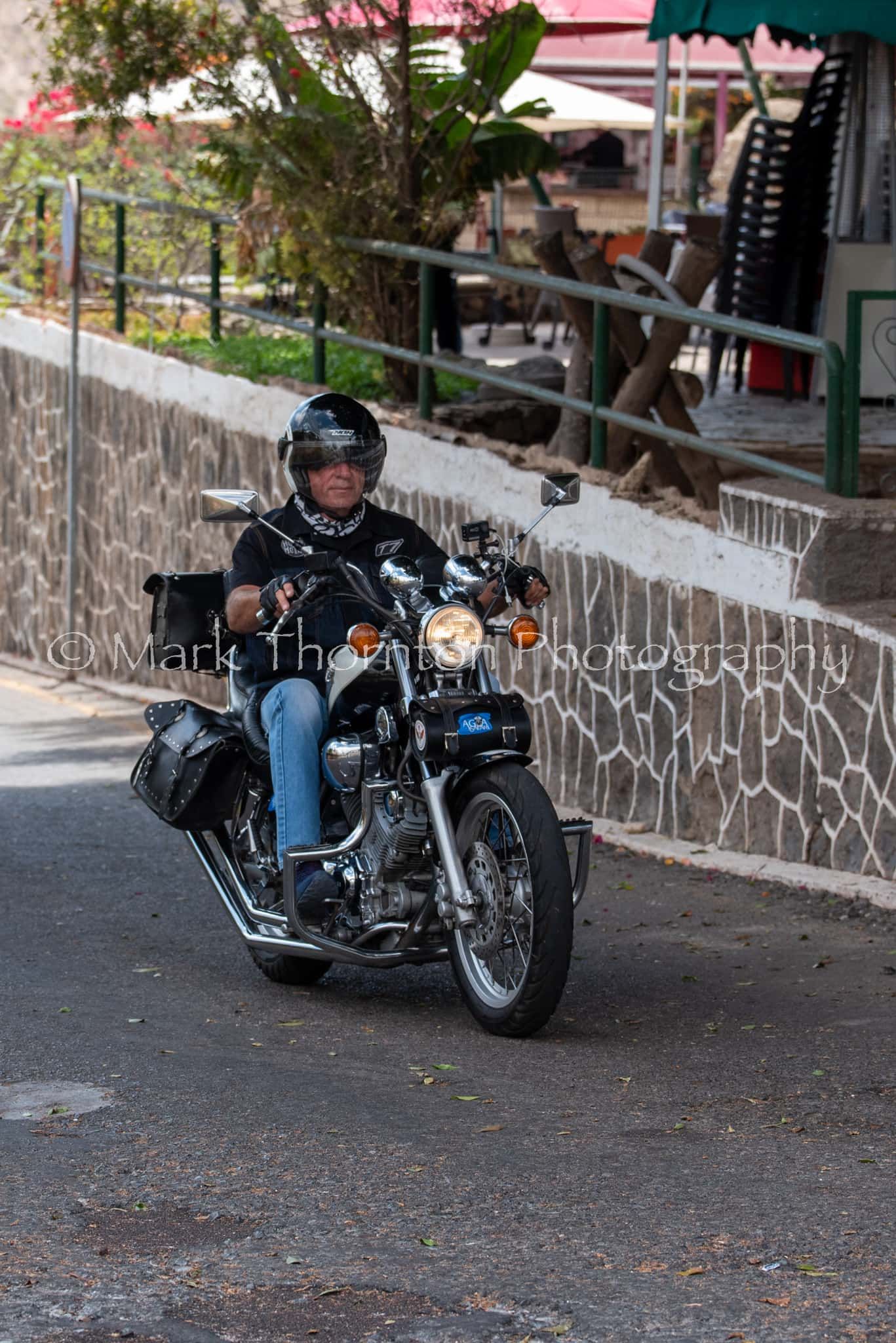 A man is riding a motorcycle down a street