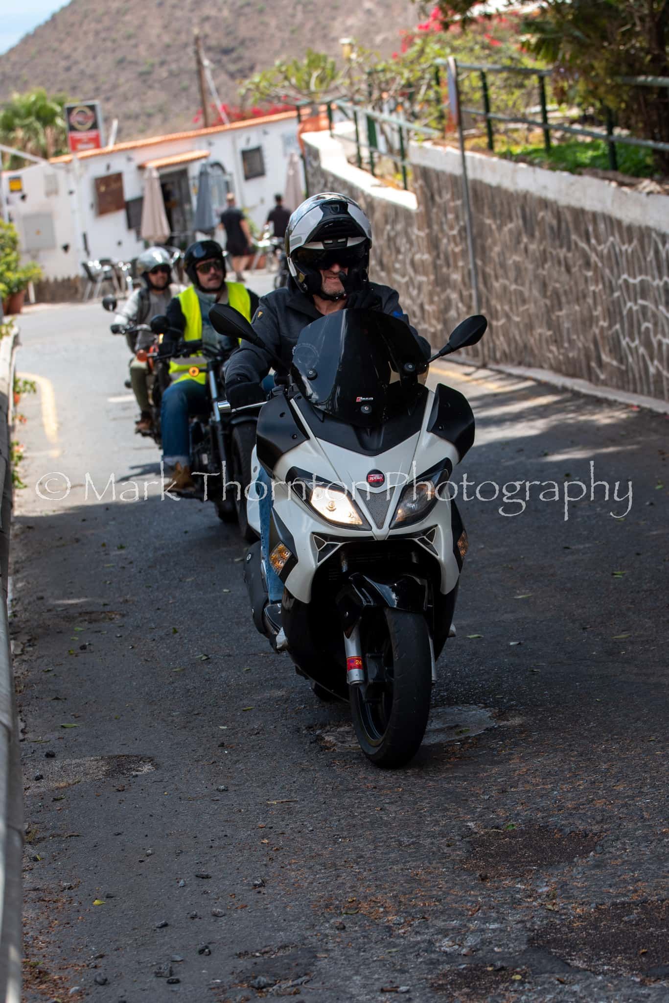A group of people are riding motorcycles down a street