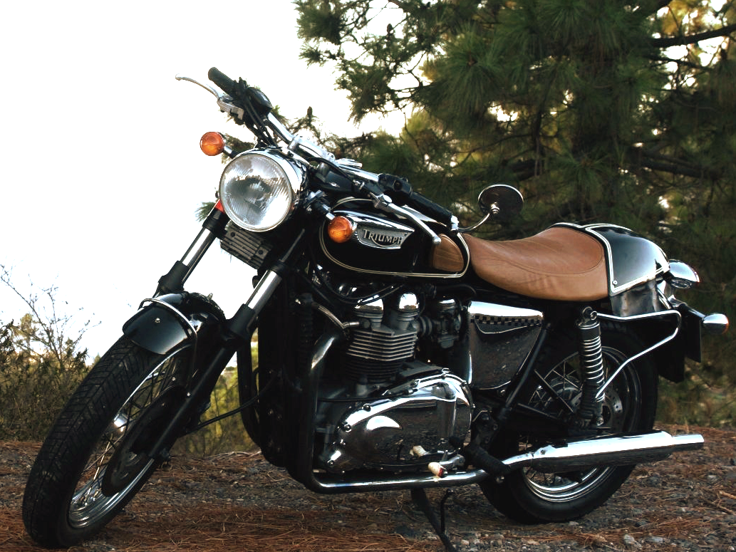 A triumph motorcycle is parked on a dirt road