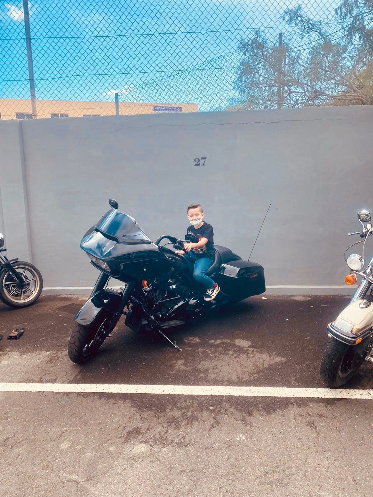 A young boy is sitting on a motorcycle in a parking lot.