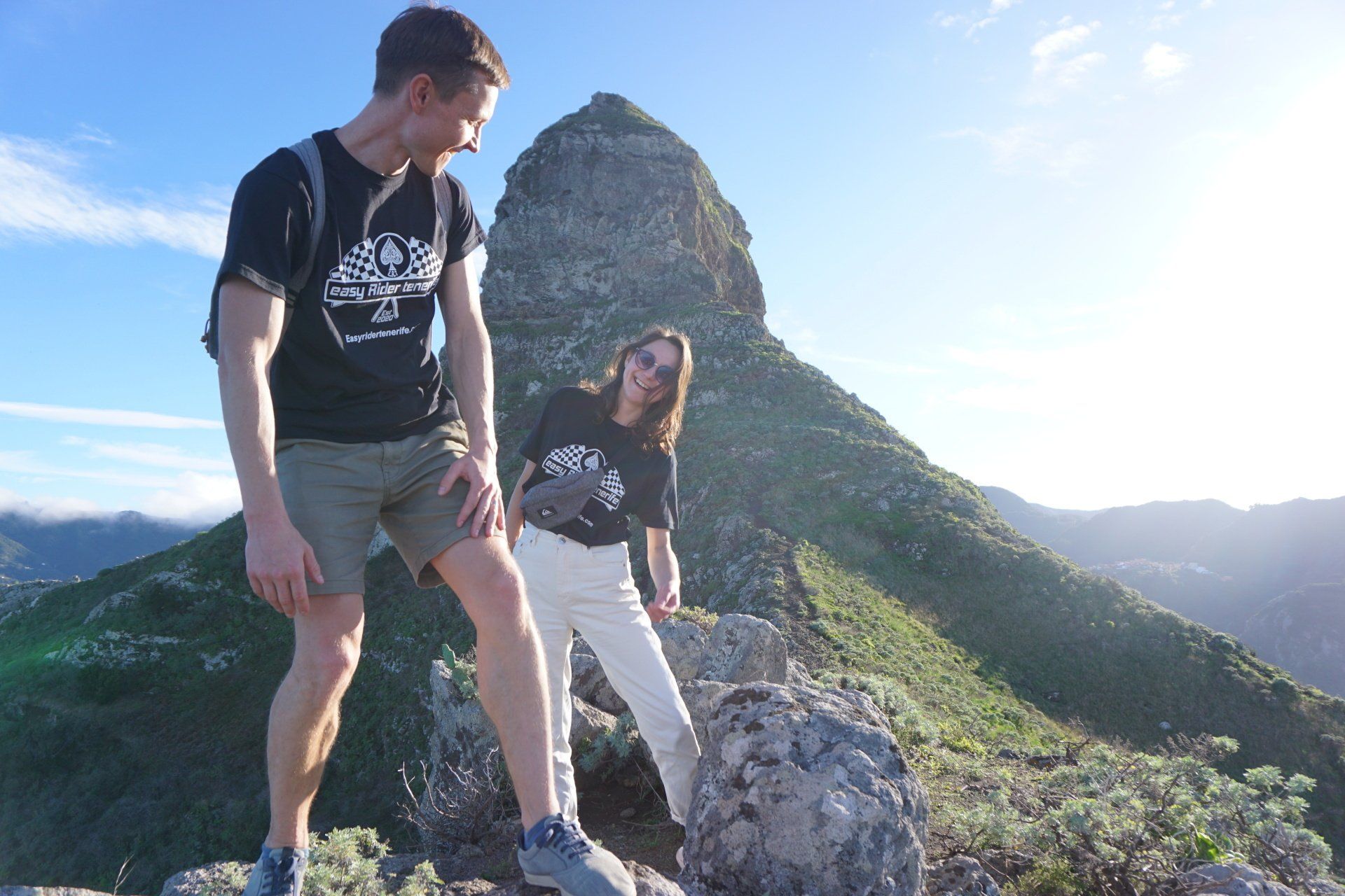 A man and a woman are standing on top of a mountain