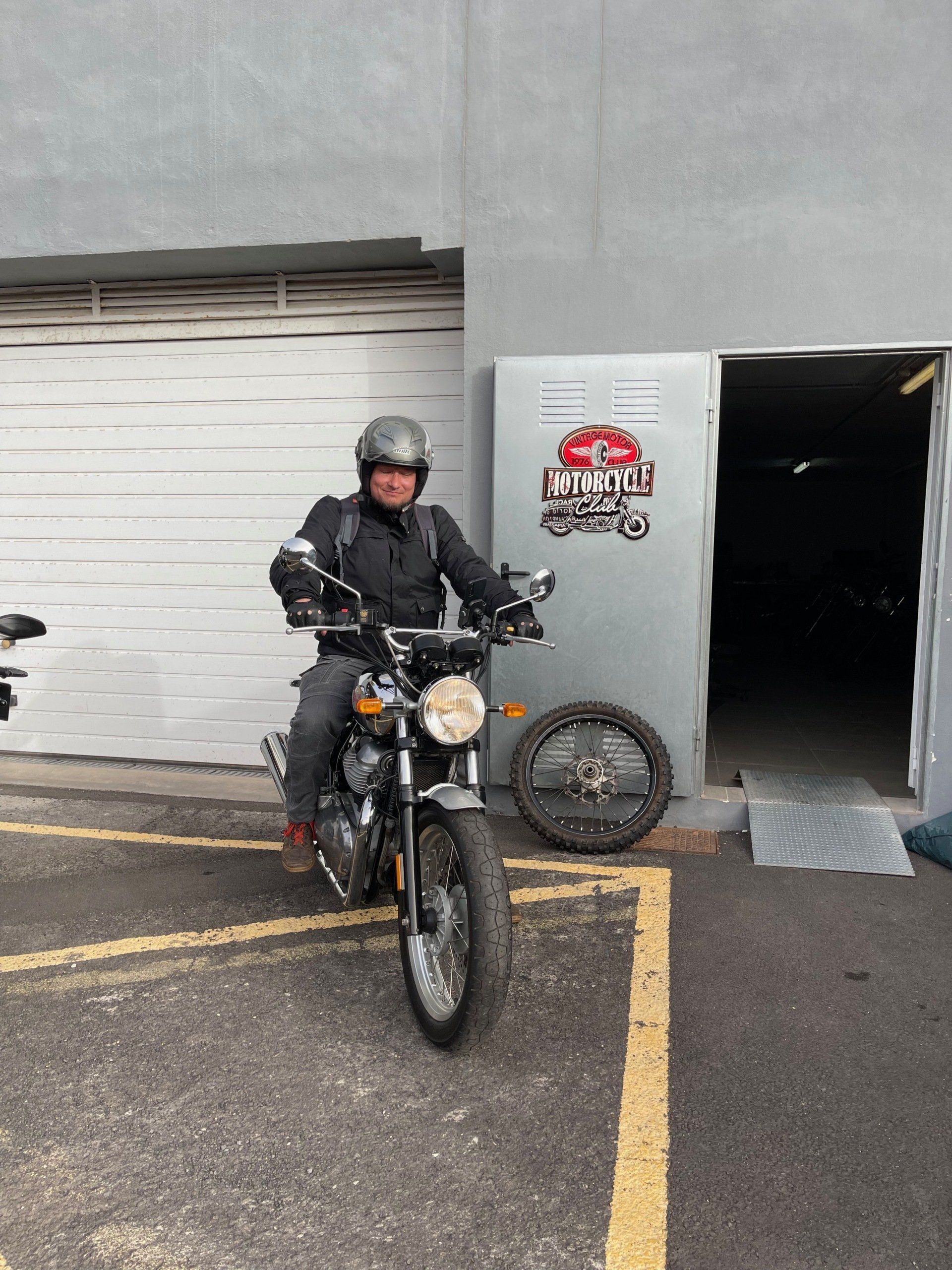 A man is riding a motorcycle in a parking lot.