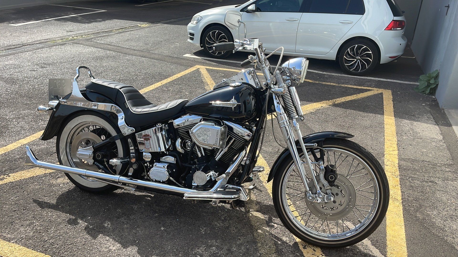 A black motorcycle is parked in a parking lot next to a white car.