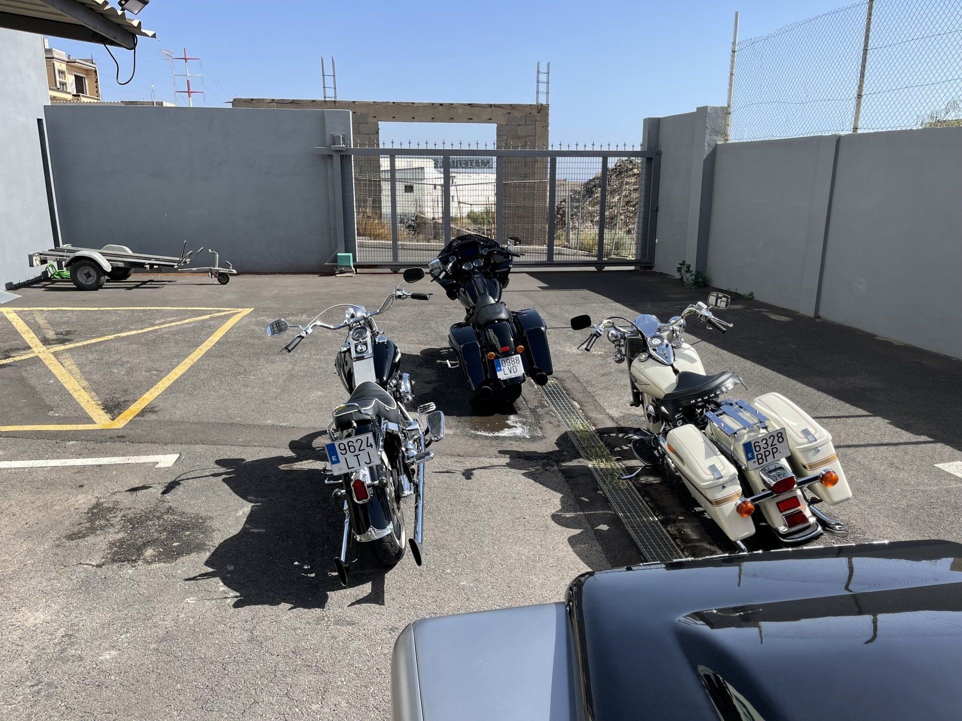 Three motorcycles are parked in a parking lot in front of a building.