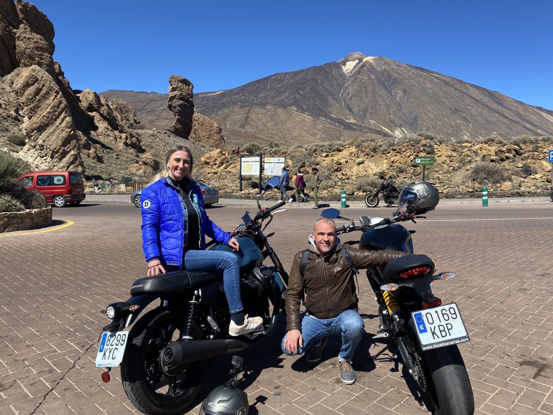 A man and a woman are sitting on motorcycles in front of a mountain.