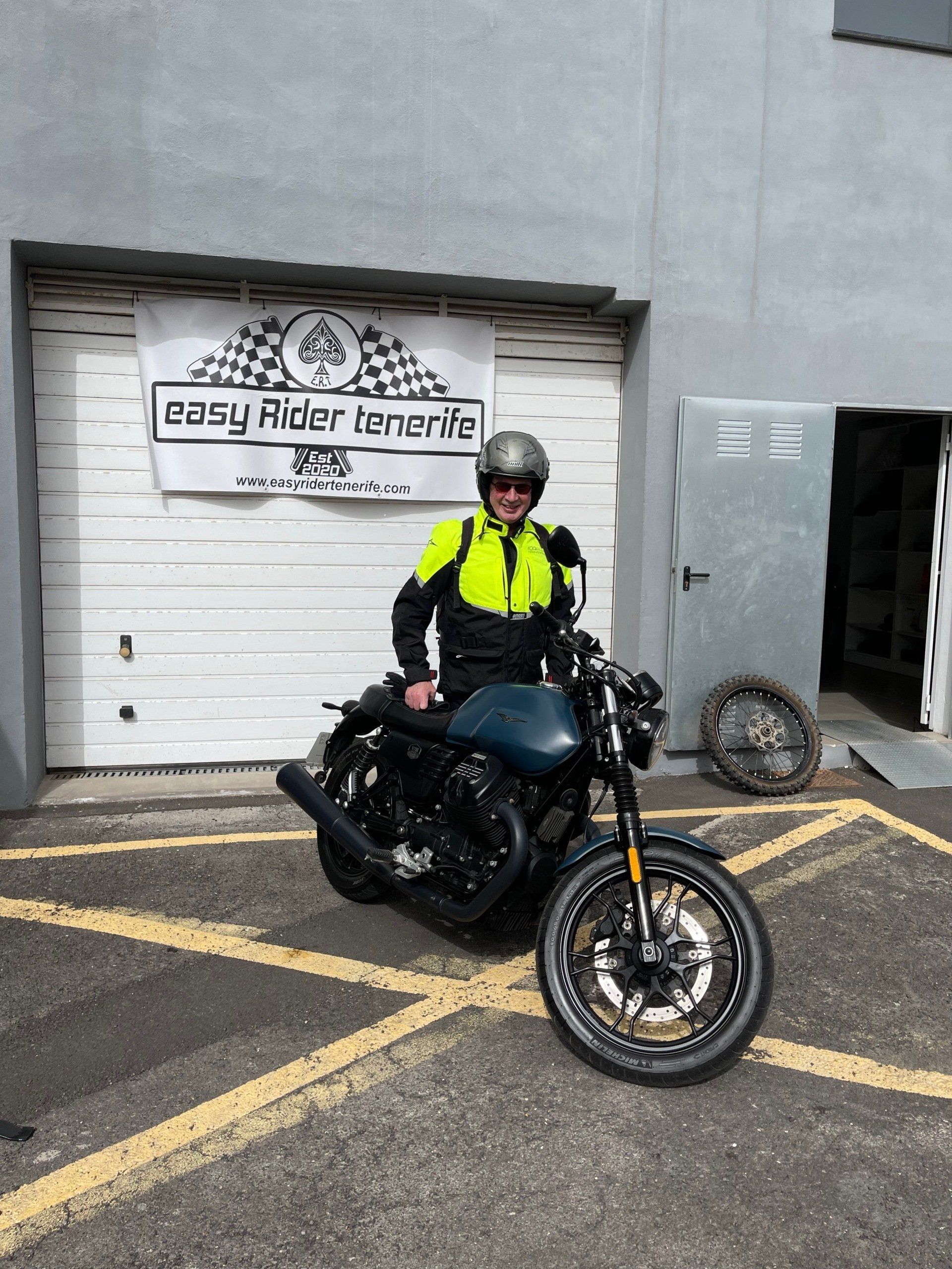 A man is riding a motorcycle in front of a garage door.