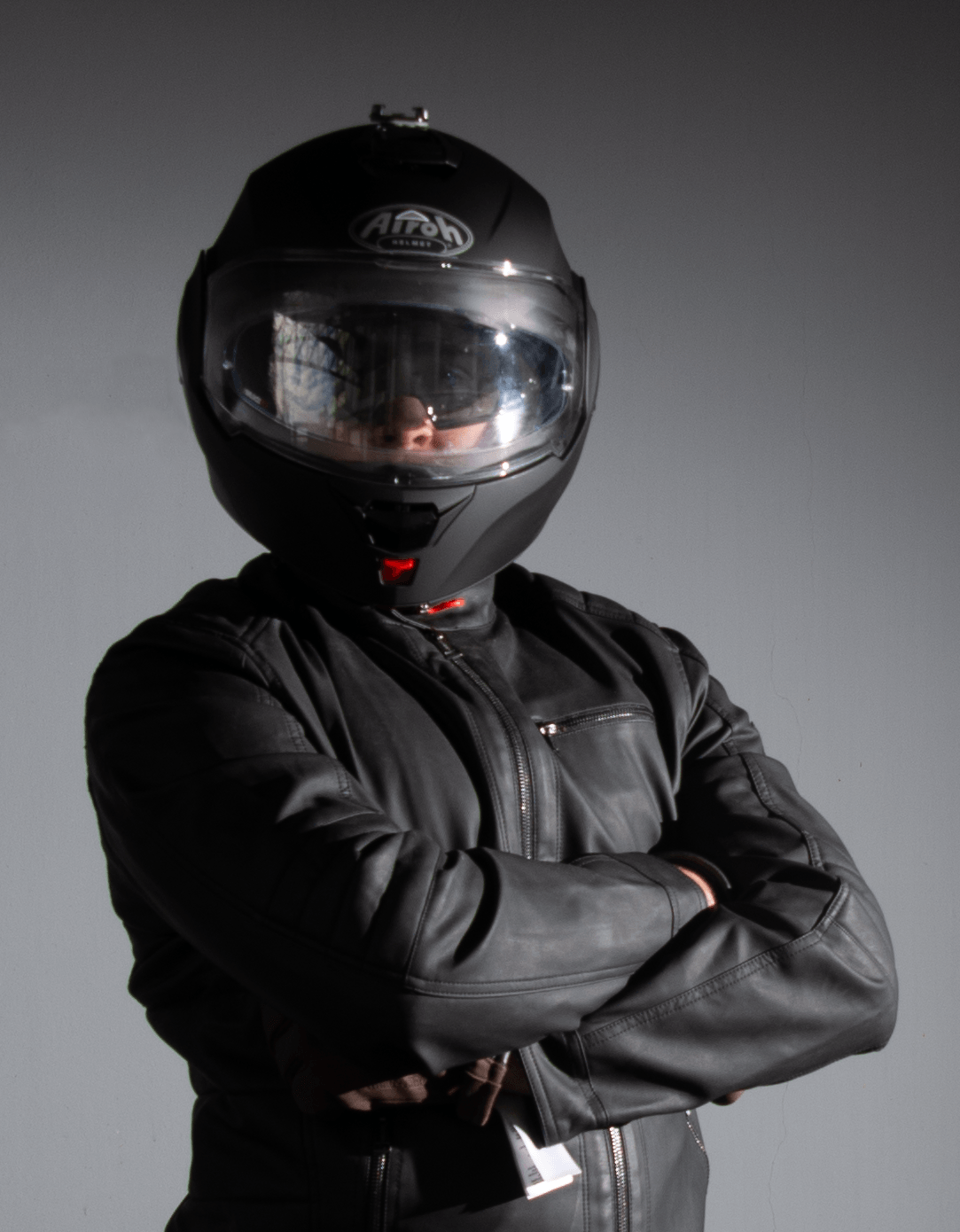 A man wearing a helmet and a leather jacket with his arms crossed