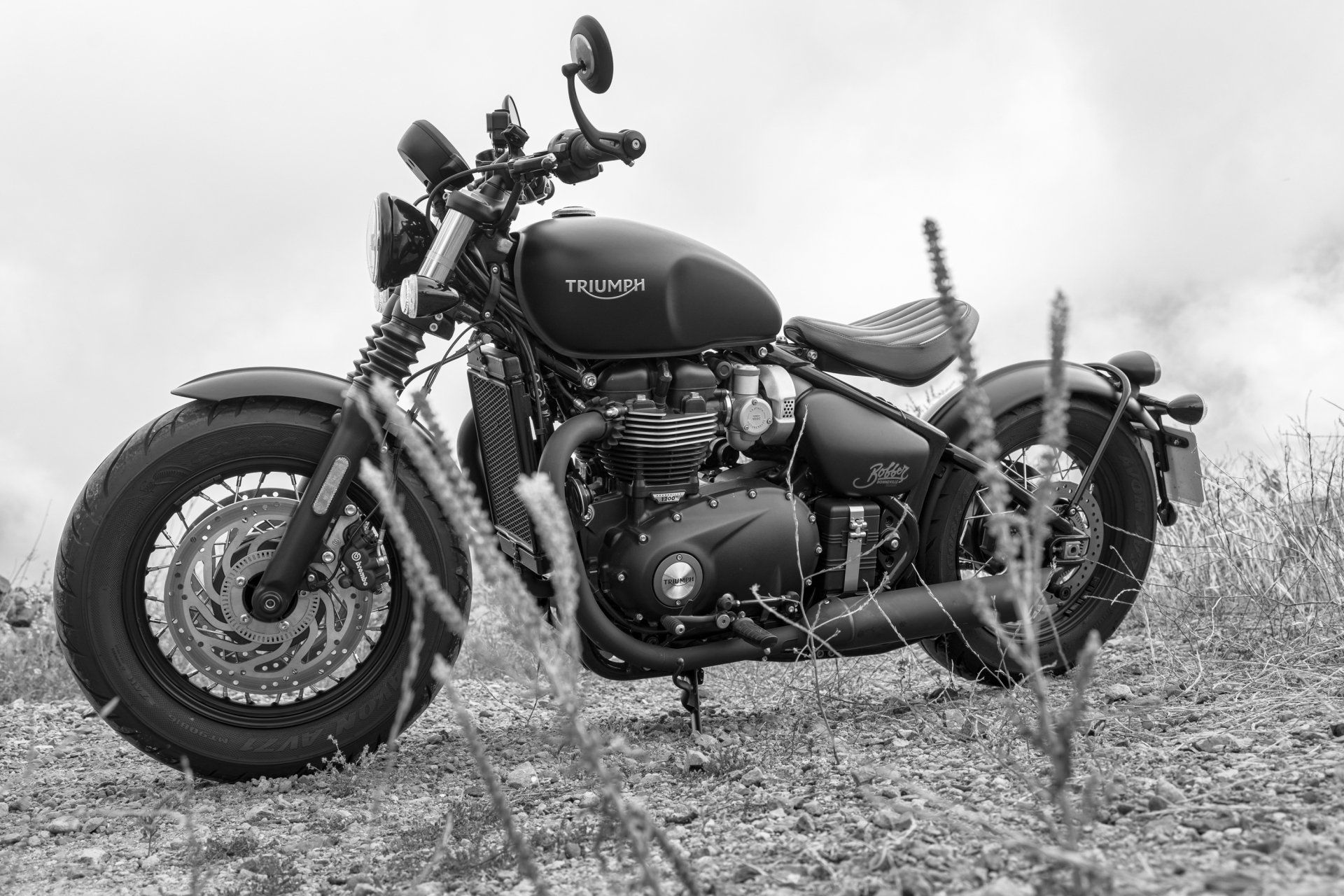 A black and white photo of a motorcycle parked in a field.