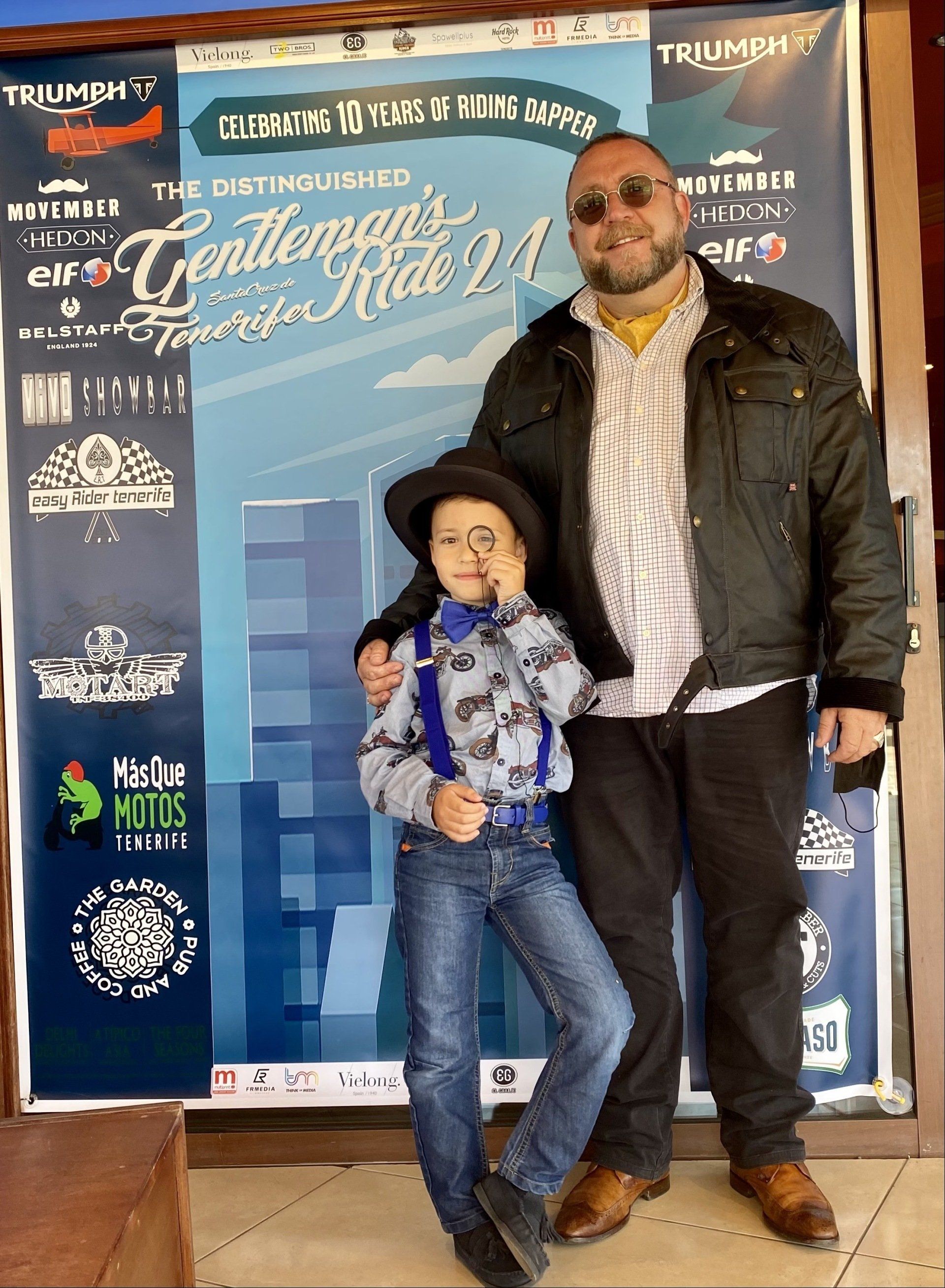 A man and a boy pose in front of a sign that says triumph