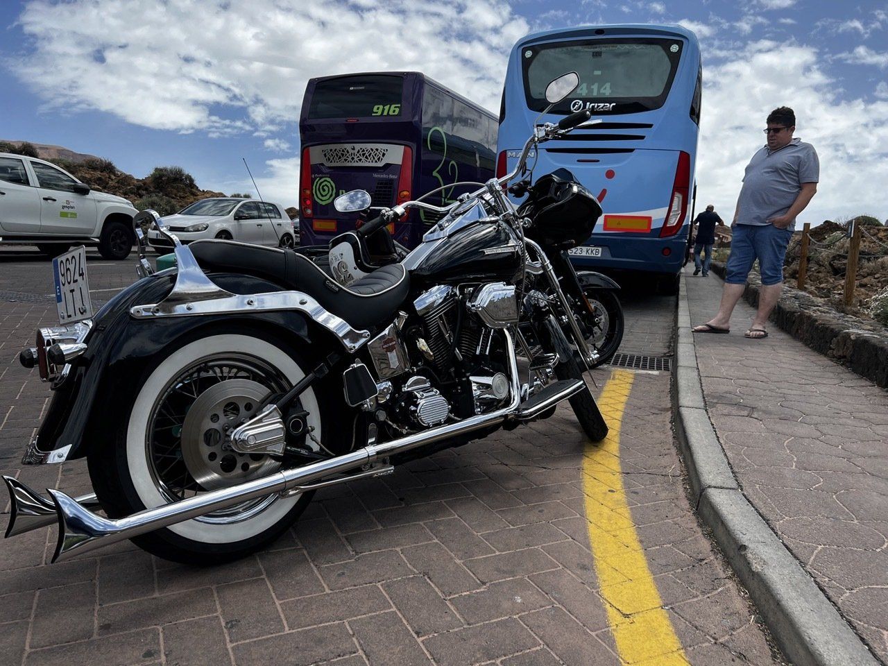 A motorcycle is parked in a parking lot next to a bus