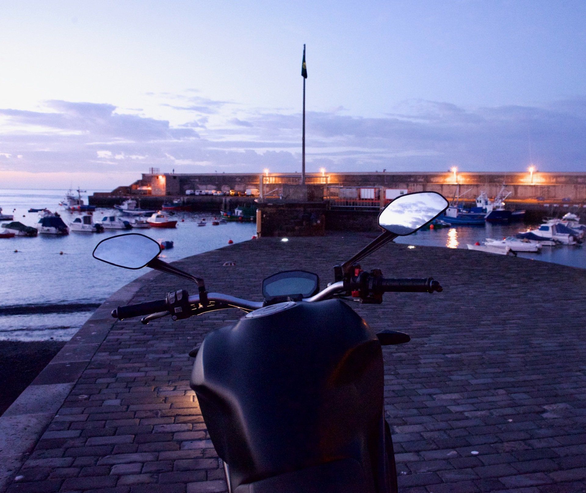 A motorcycle is parked in front of a harbor at night
