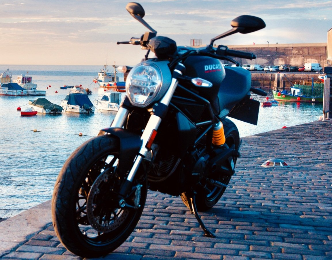A black ducati motorcycle is parked on a cobblestone street