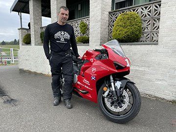 A man is standing next to a red motorcycle.