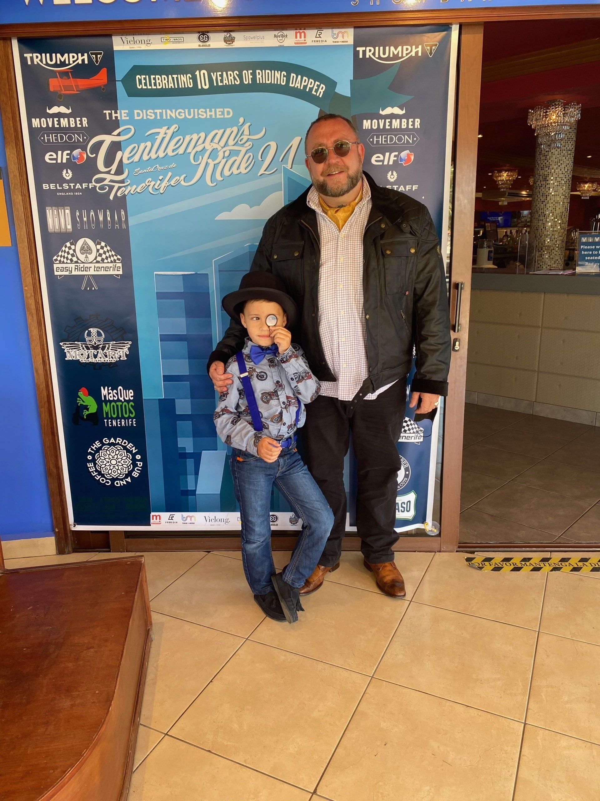 A man and a boy are posing for a picture in front of a sign.
