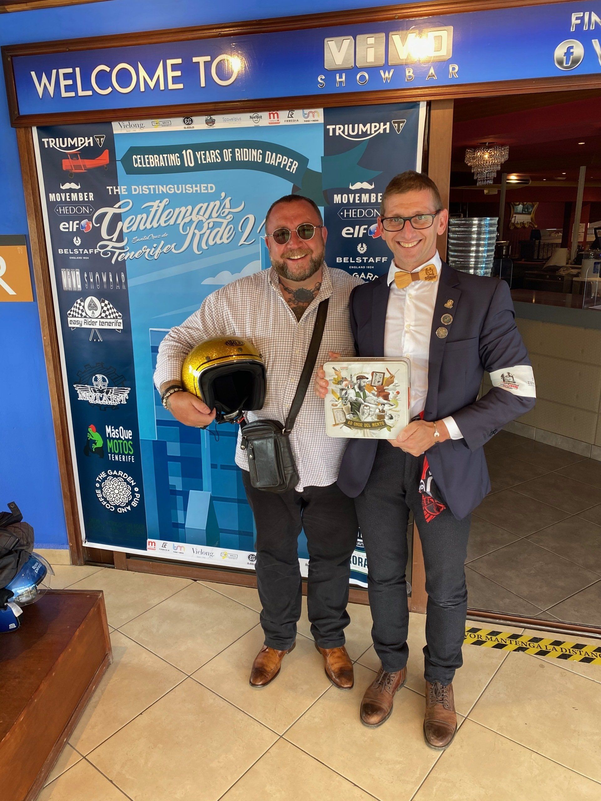 Two men are standing in front of a sign that says welcome to