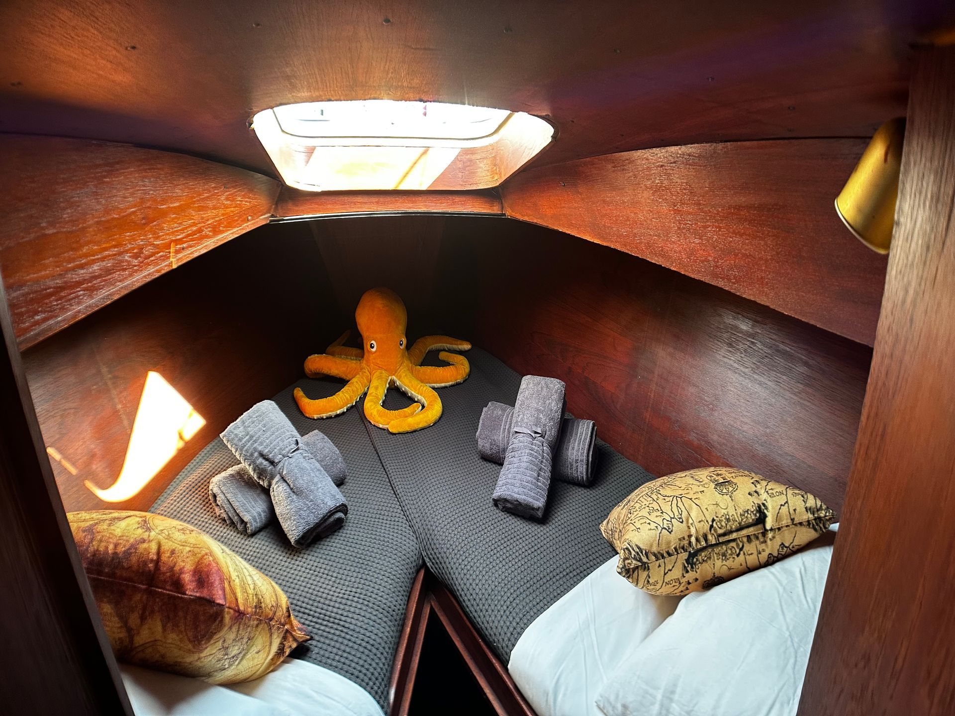 A bedroom on a boat with two beds and an octopus on the bed.