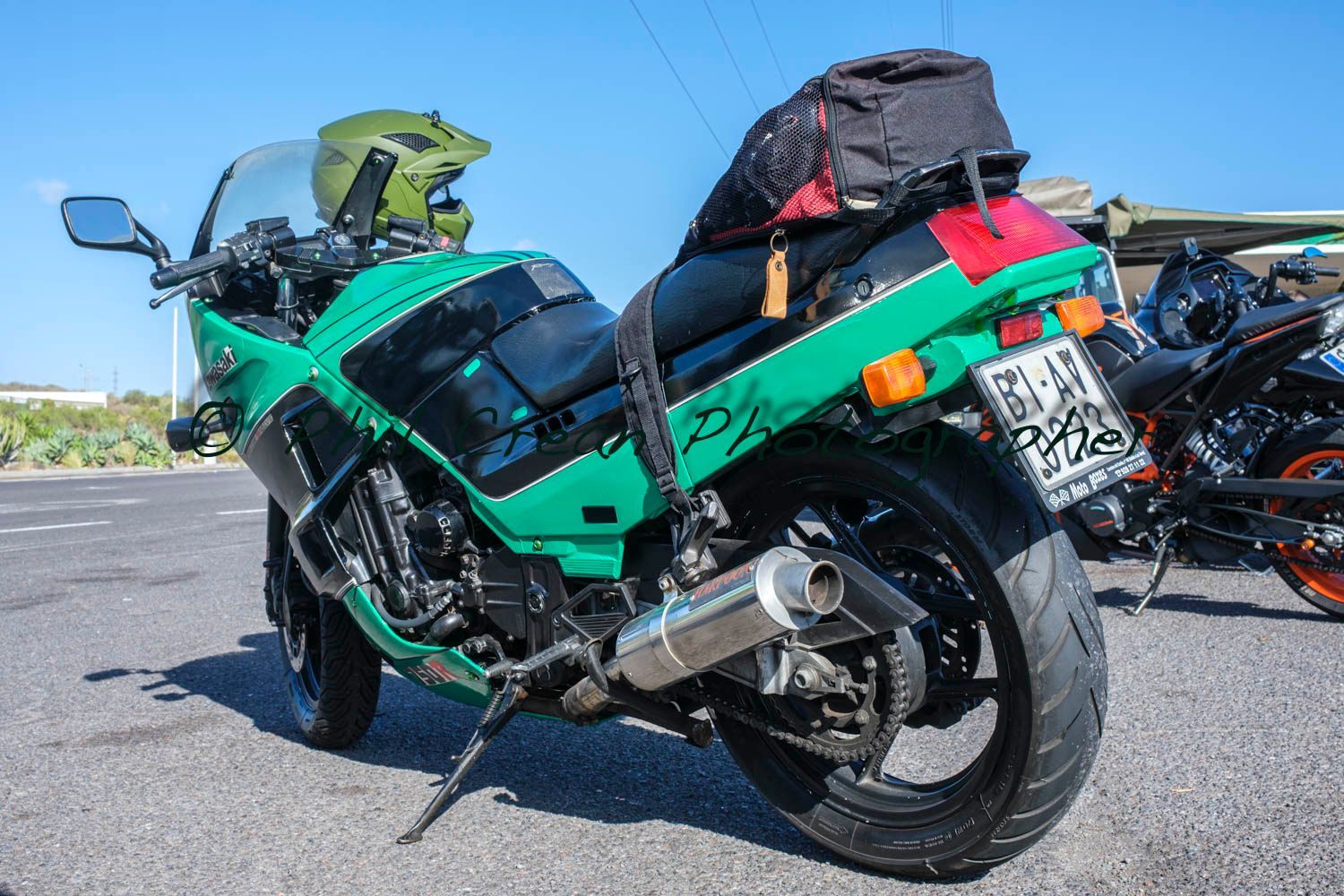 A green motorcycle is parked on the side of the road.