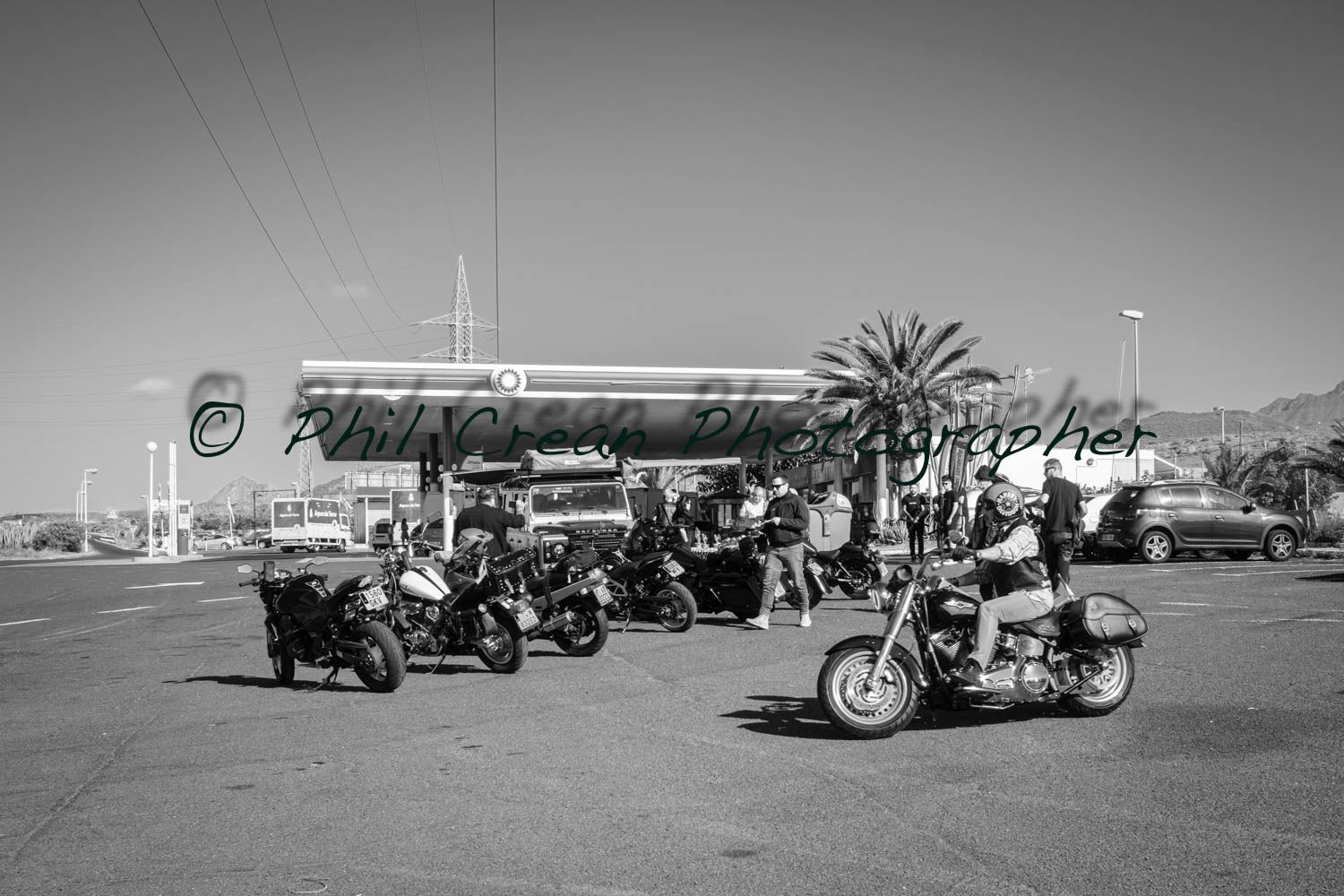 A black and white photo of motorcycles parked in front of a gas station